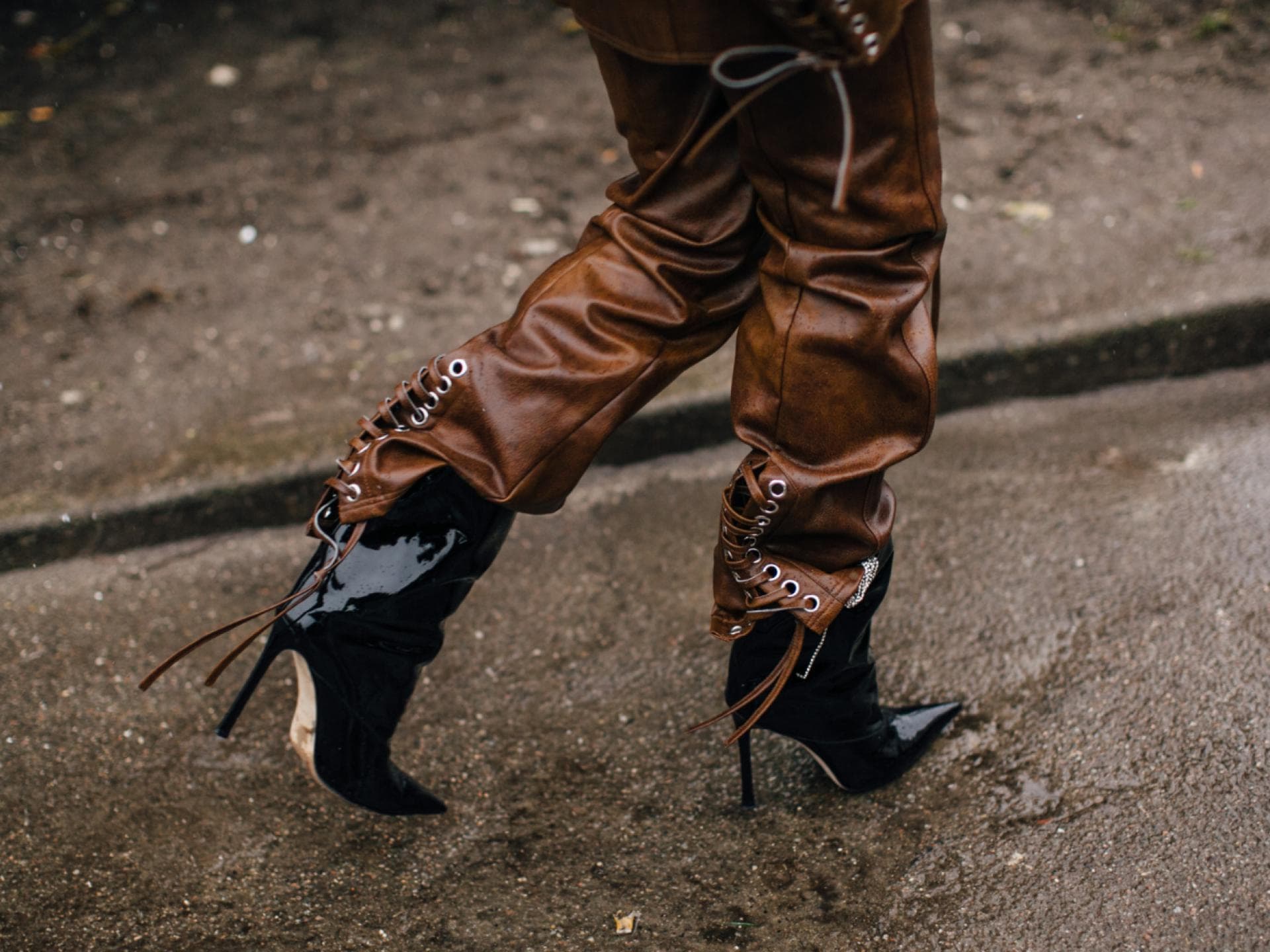 Frau trägt braune Lederhose und schwarze Lack Stiefel Streetstyle Frau trägt braune Lederhose und schwarze Lack Stiefel Streetstyle