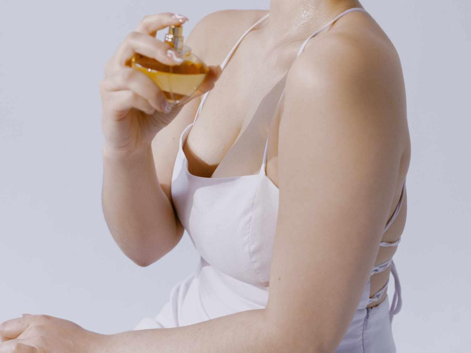 Frau mit Parfum in der Hand und Kleid