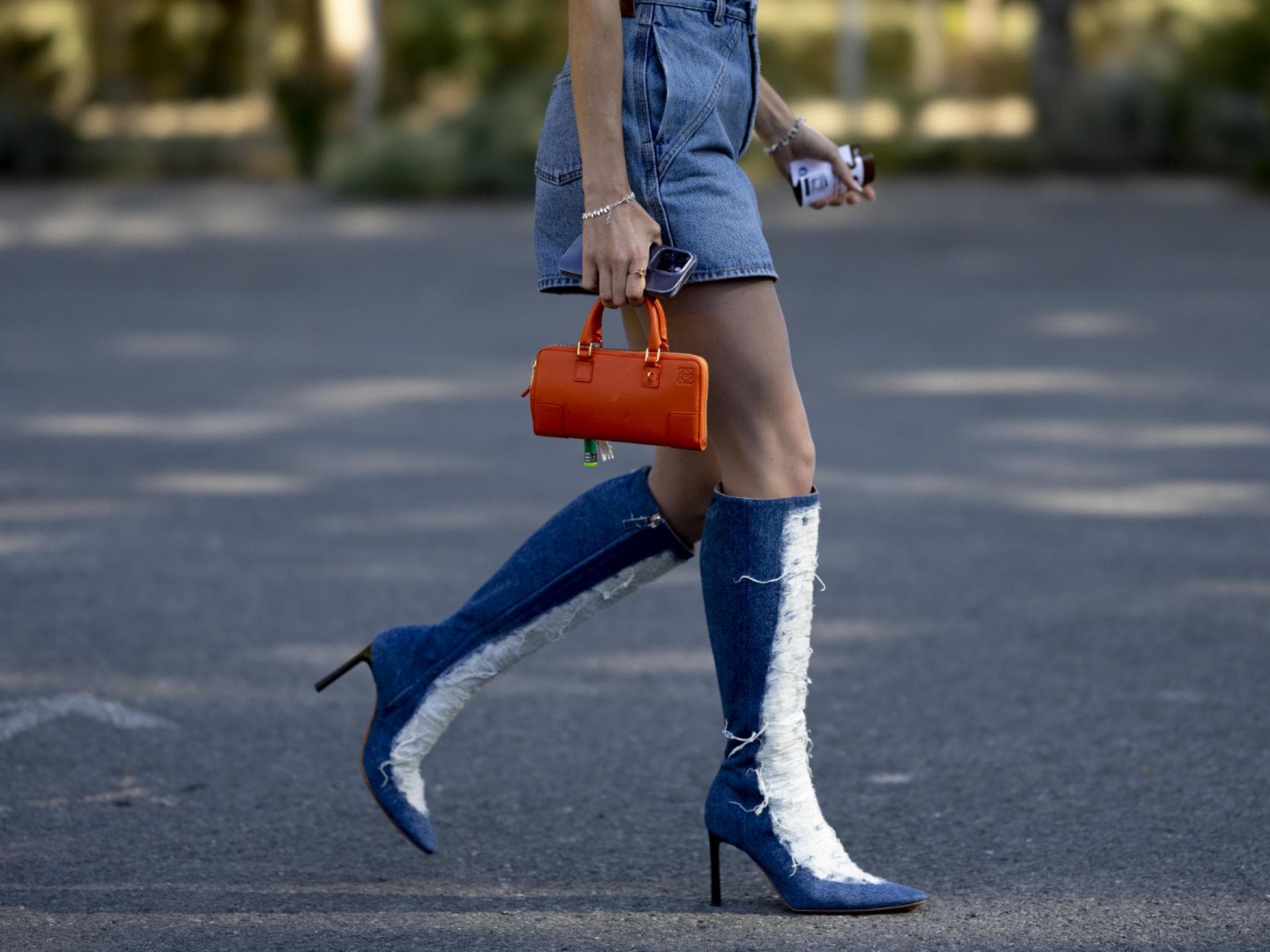 Frau trägt Jeans Stiefel und Jeansrock orangene Tasche Streetstyle Frau trägt Jeans Stiefel und Jeansrock orangene Tasche Streetstyle