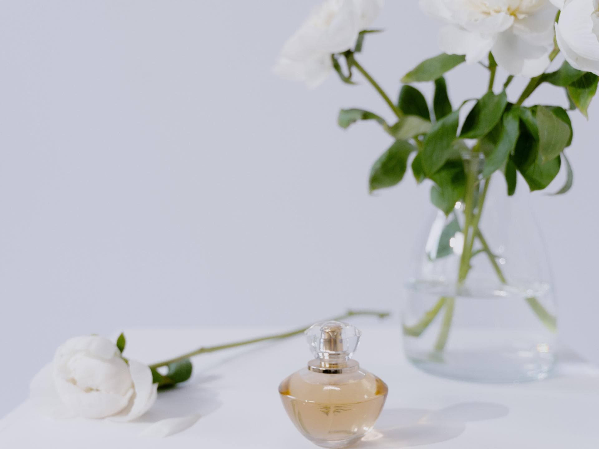 Parfum Flakon vor Vase mit Blumen