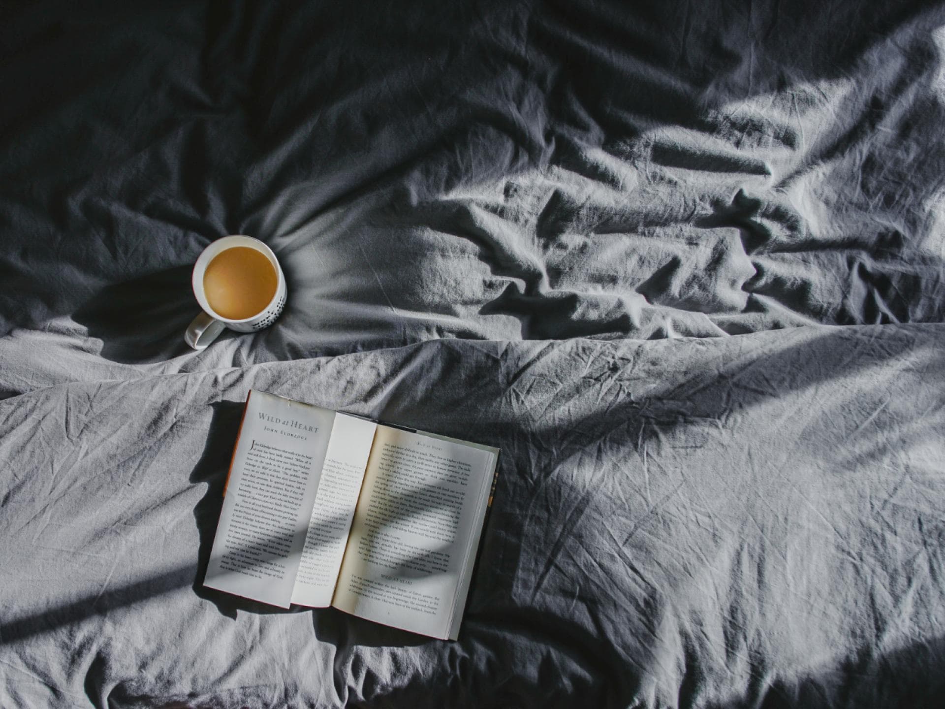 Bett mit Tasse Kaffee Bettdecke und Buch