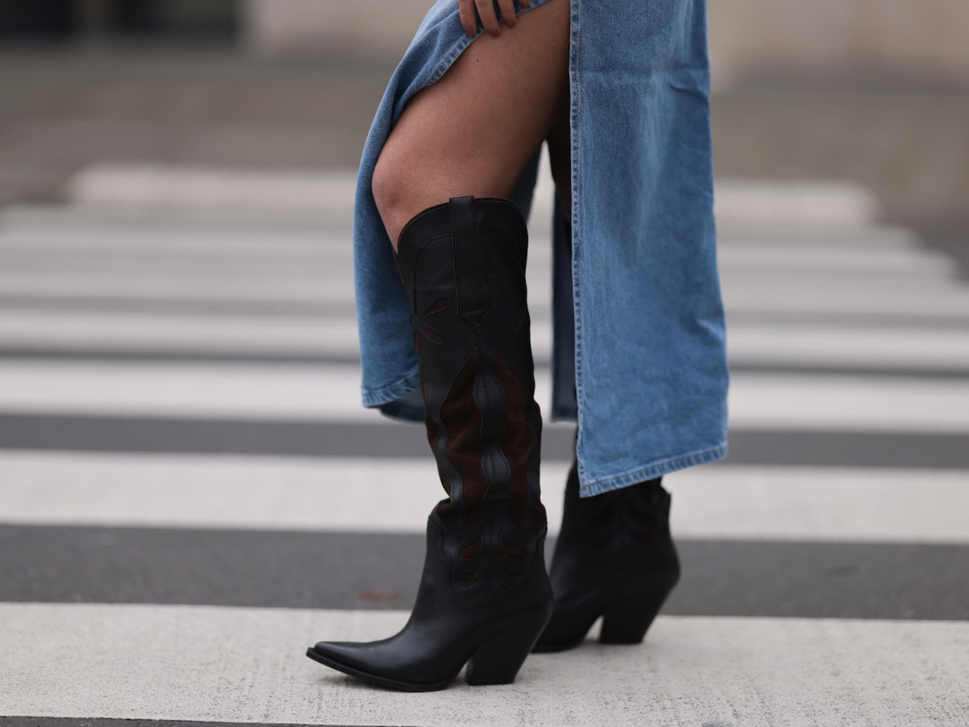 Cowboystiefel kombinieren: Die besten Styling-Tipps Cowboystiefel kombinieren: Eine Frau trägt Cowboystiefel zum Jeansrock