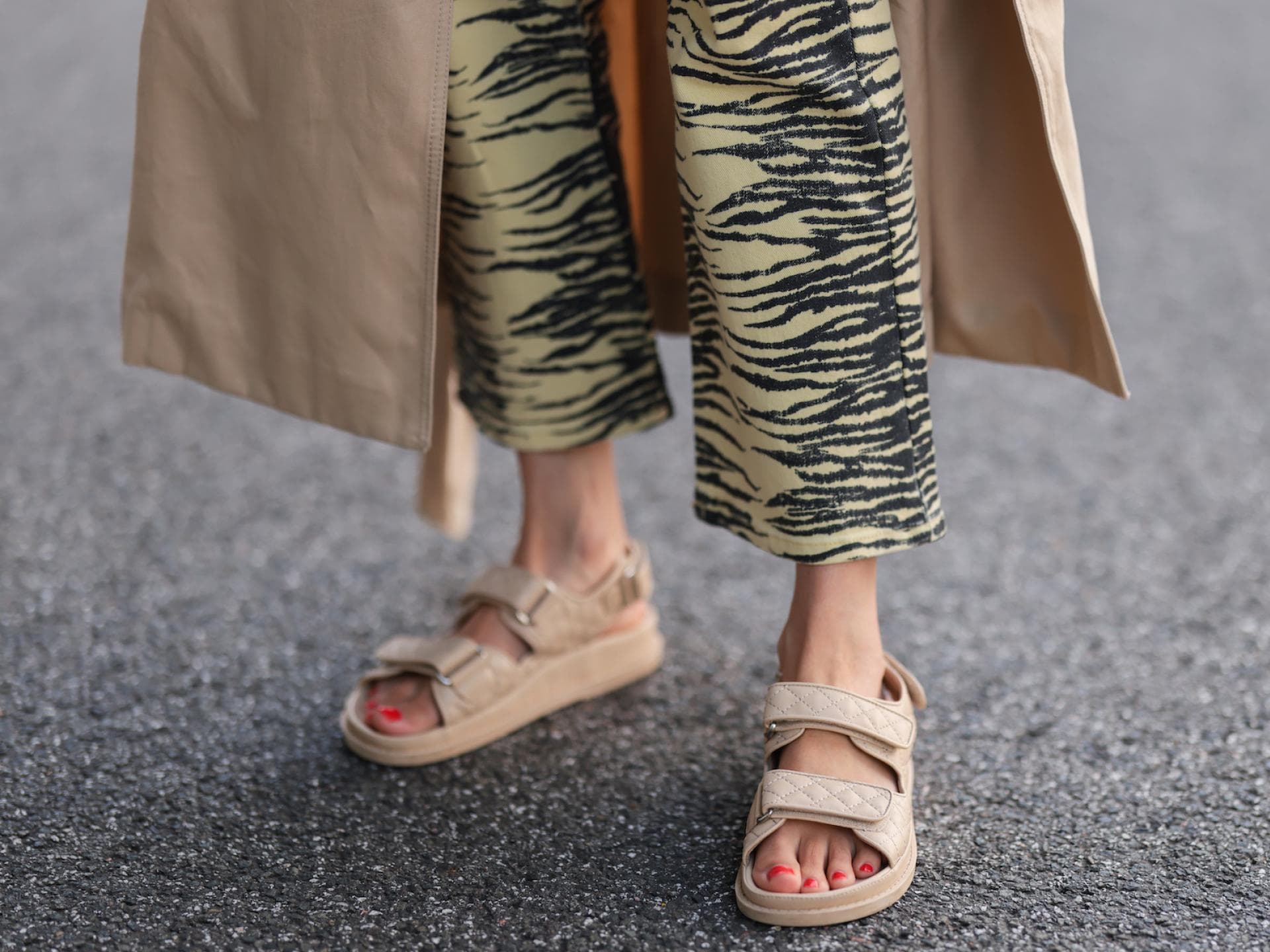 Frau trägt beige Sandalen und eine gemusterte Hose