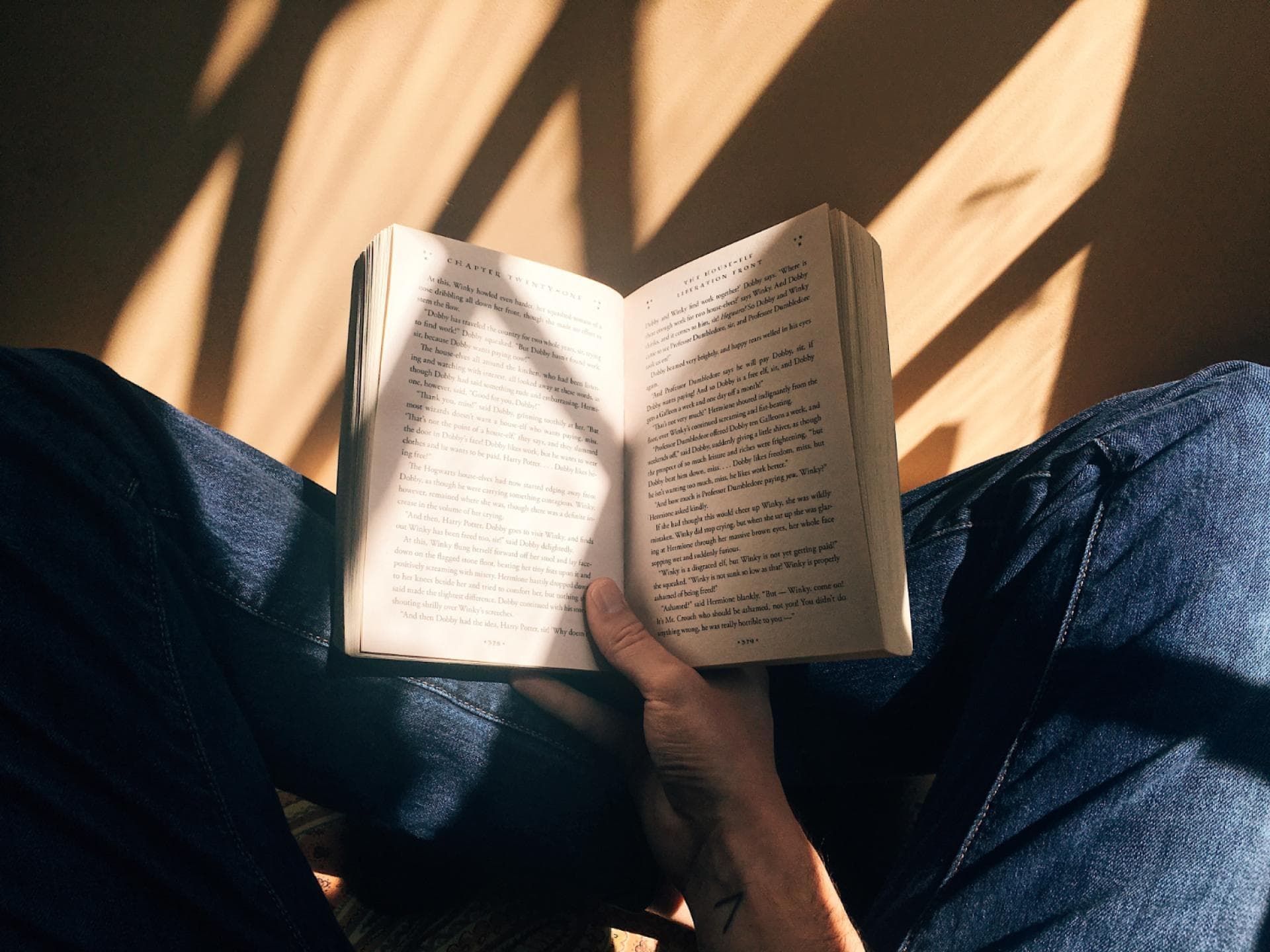 Person sitzt auf Boden und liest Buch