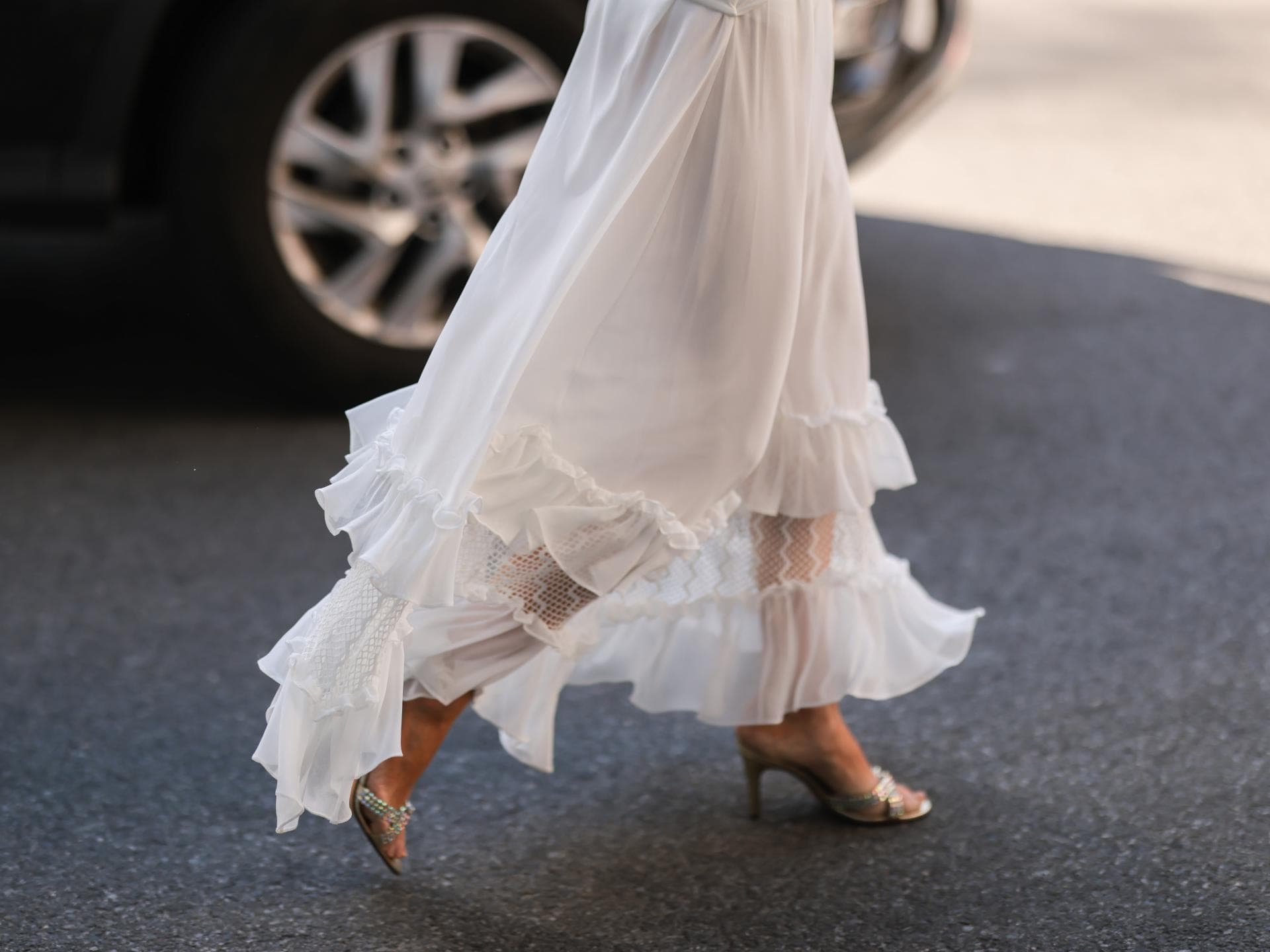 Frau trägt silberne Schuhe zum weißen Kleid