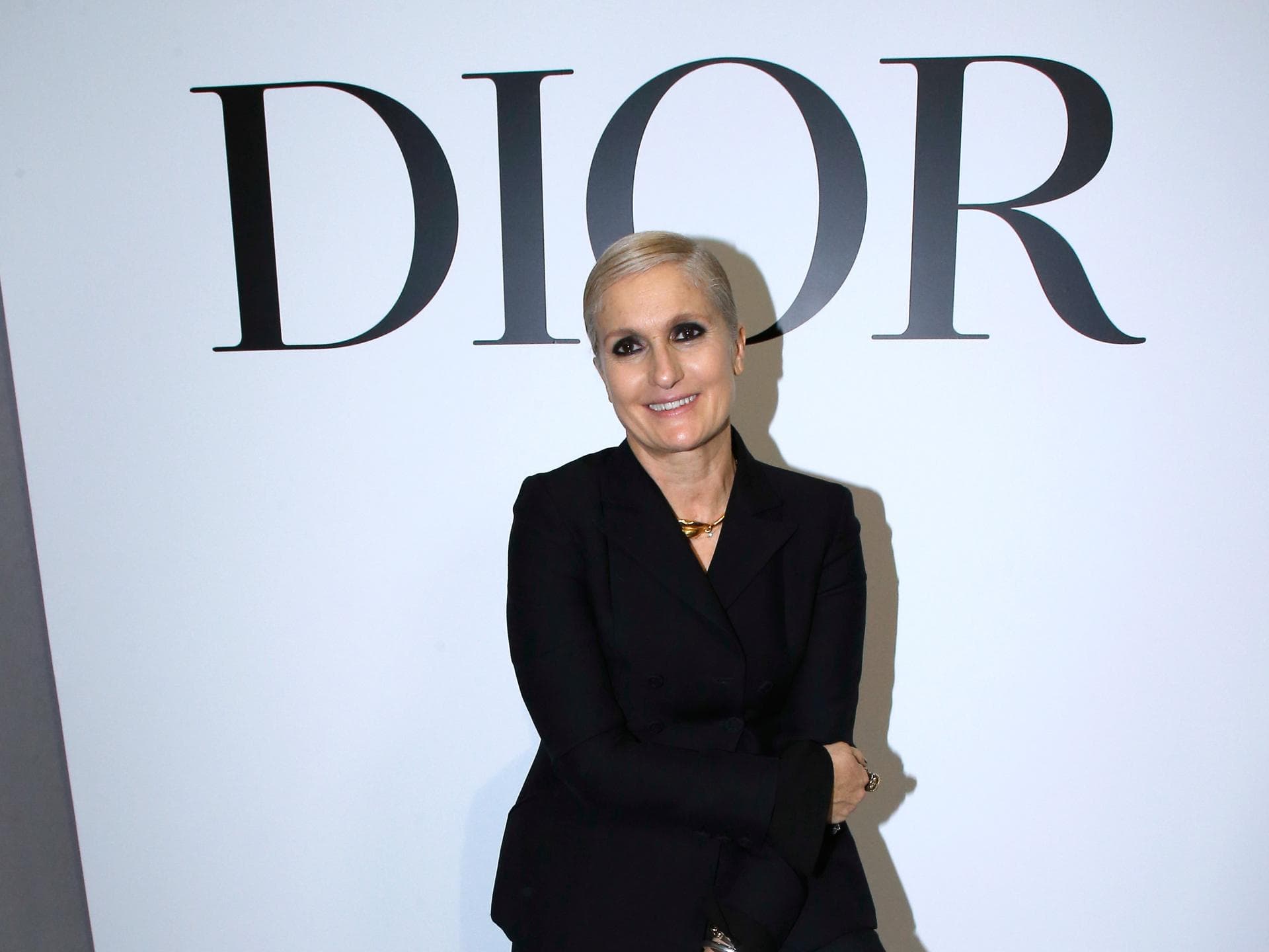 Maria Grazia Chiuri sitzt vor Dior Schild