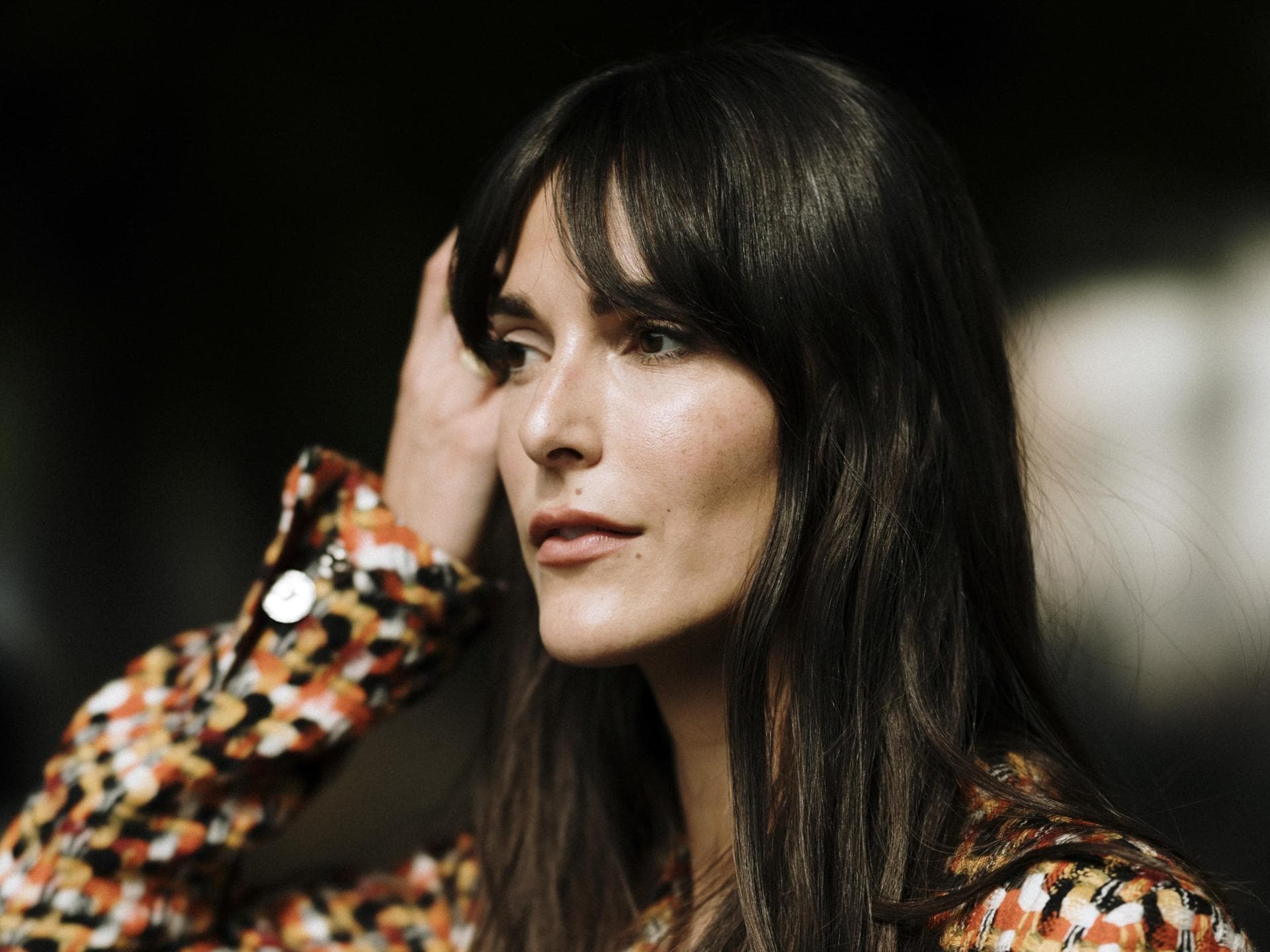 Paris Fashion Week Streetstyle Frau trägt Jacke mit Karomuster lange braune Haare und Pony