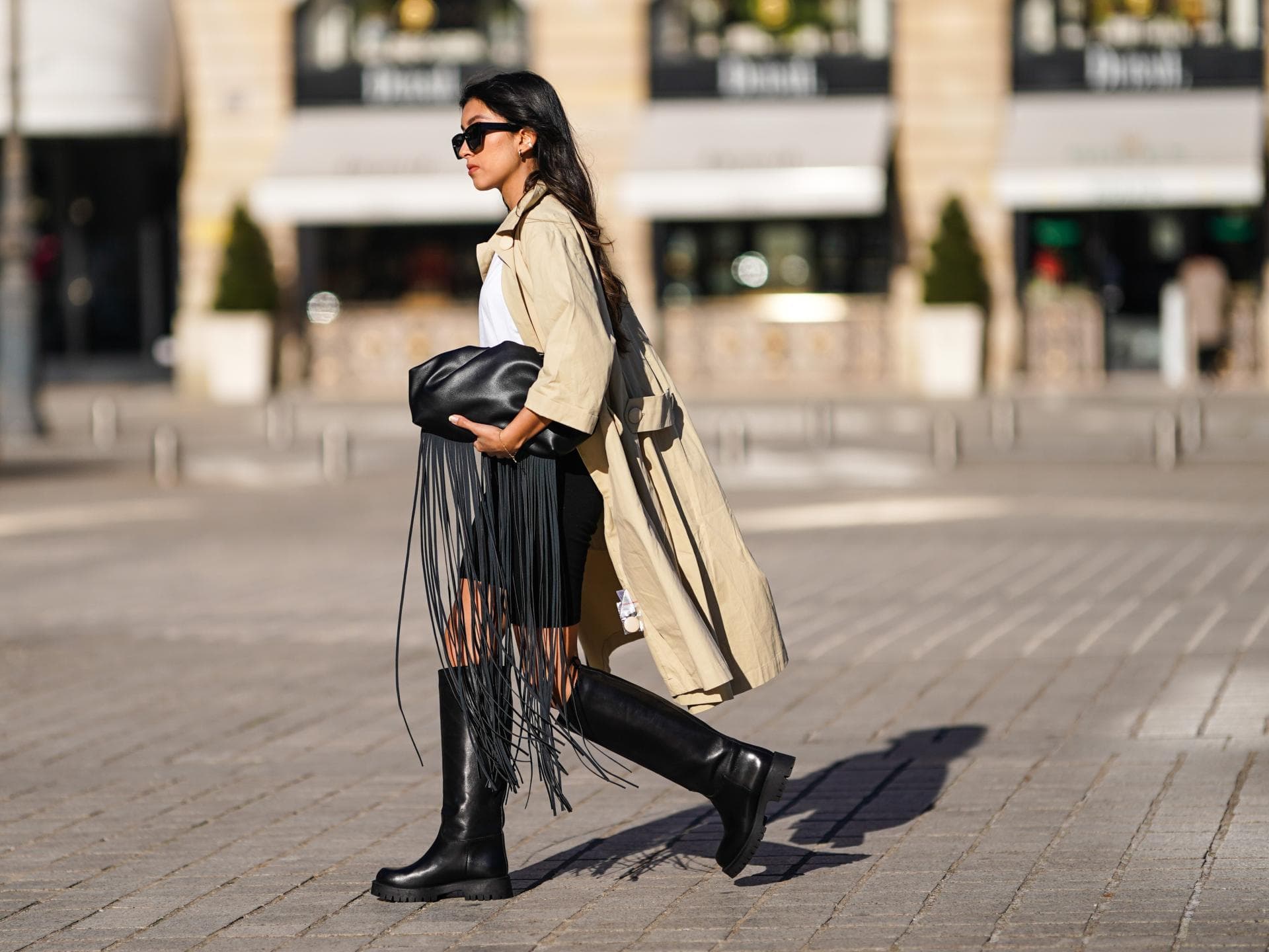 Eine Frau trägt eine Radlerhose, Stiefel und einen Trenchcoat