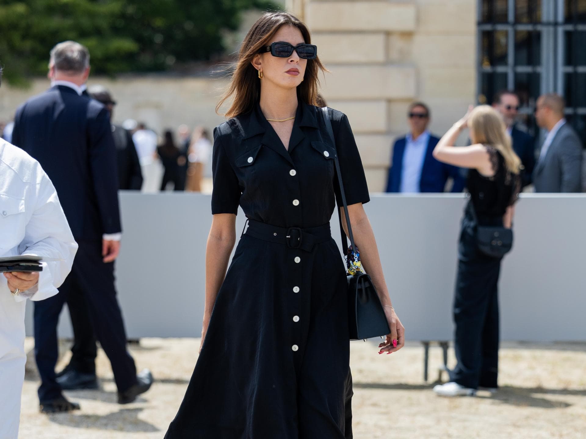Frau in Paris trägt schwarzes Kleid mit Stiefeln