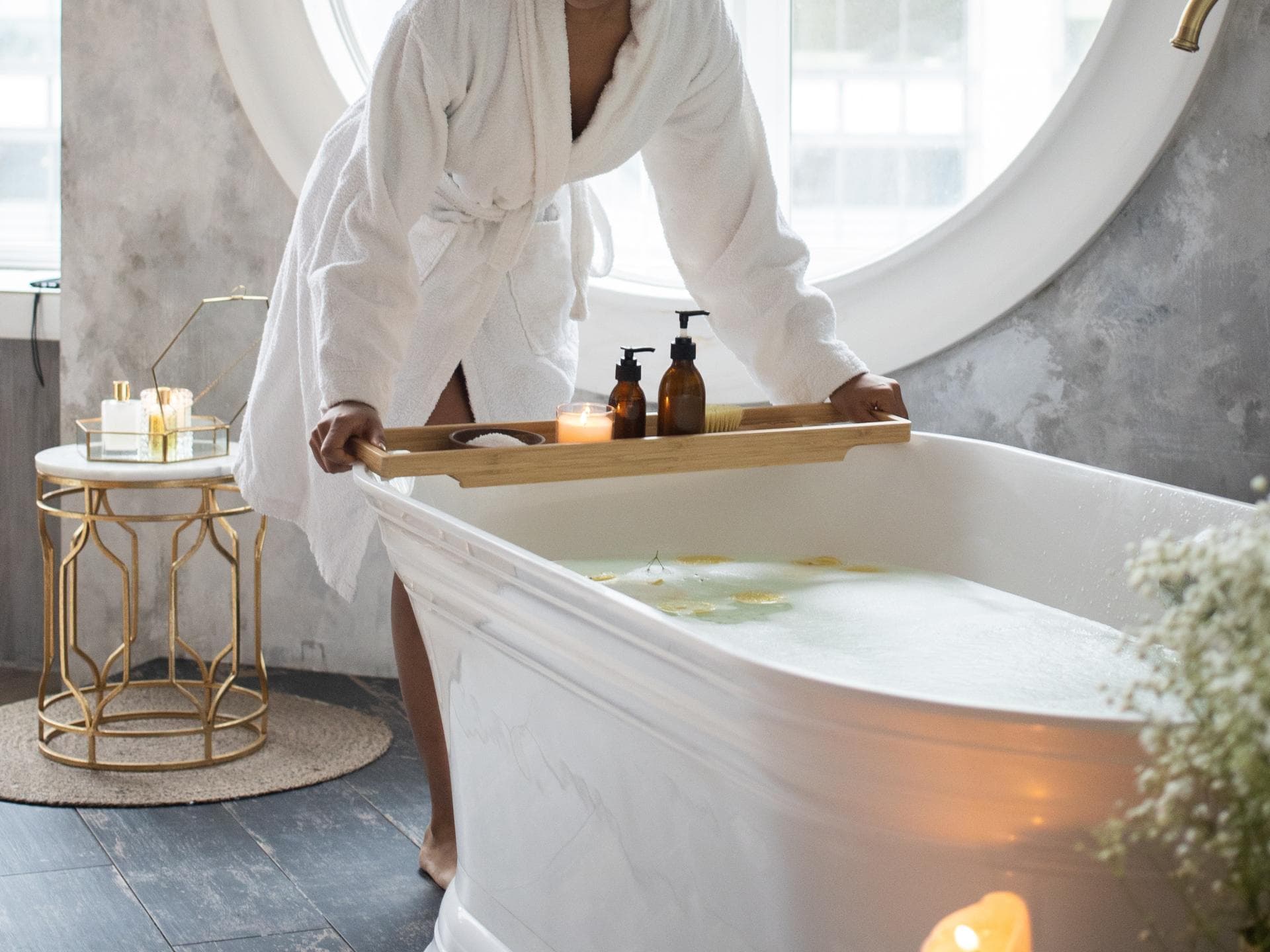 Frau im Bademantel stellt ein Tablett auf die Badewanne