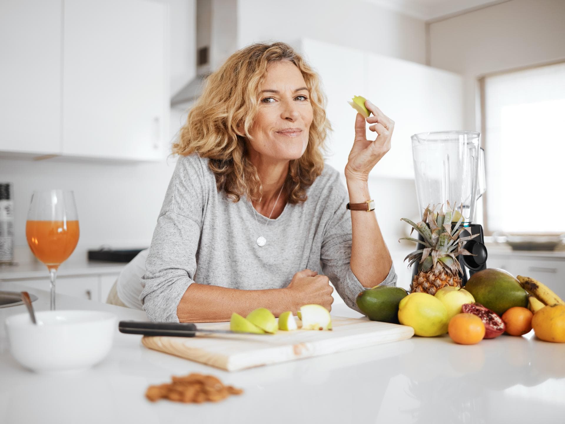 Frau ab 50 isst Obst in der Küche