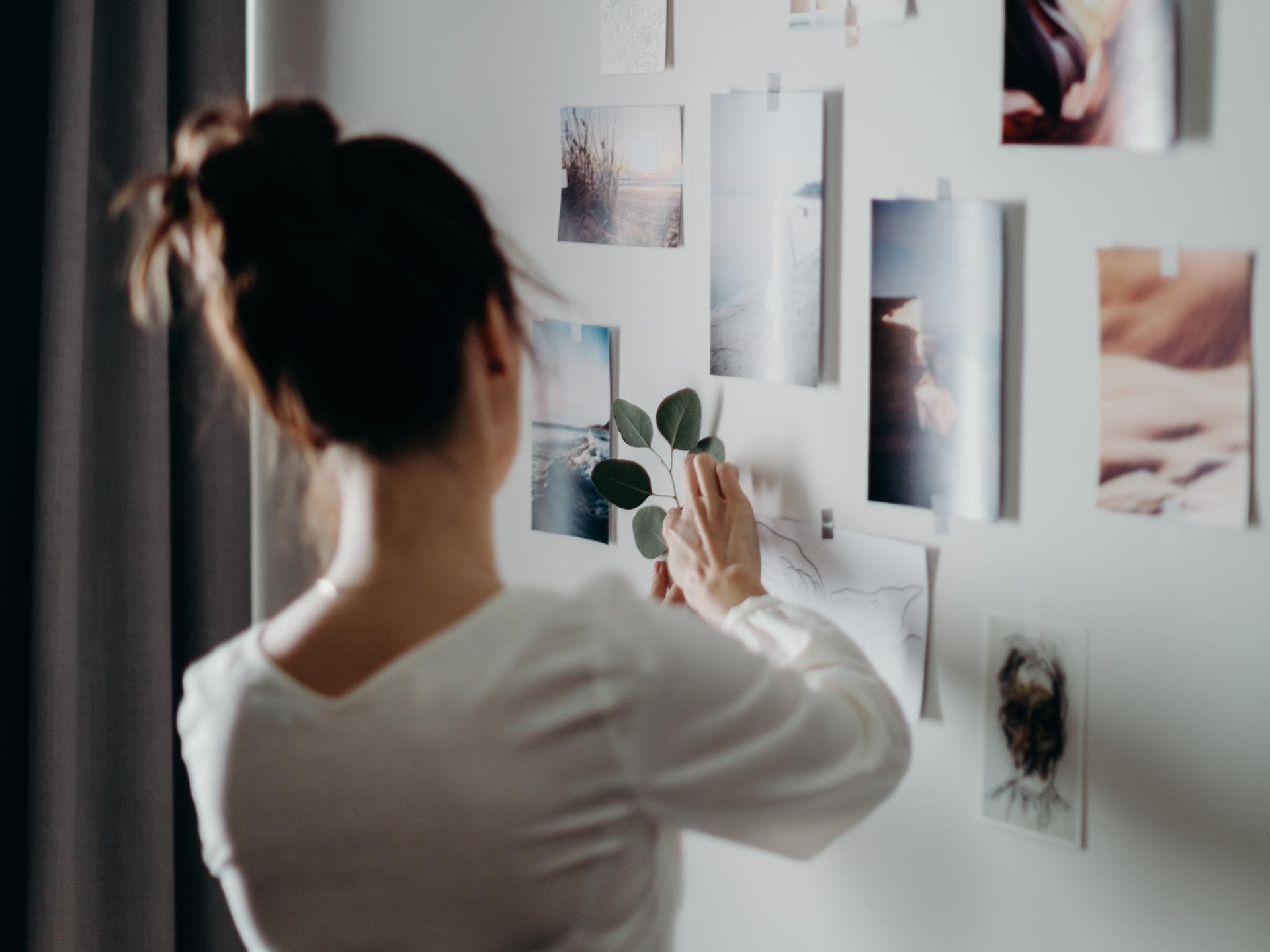Frau dekoriert eine Wand mit Fotos