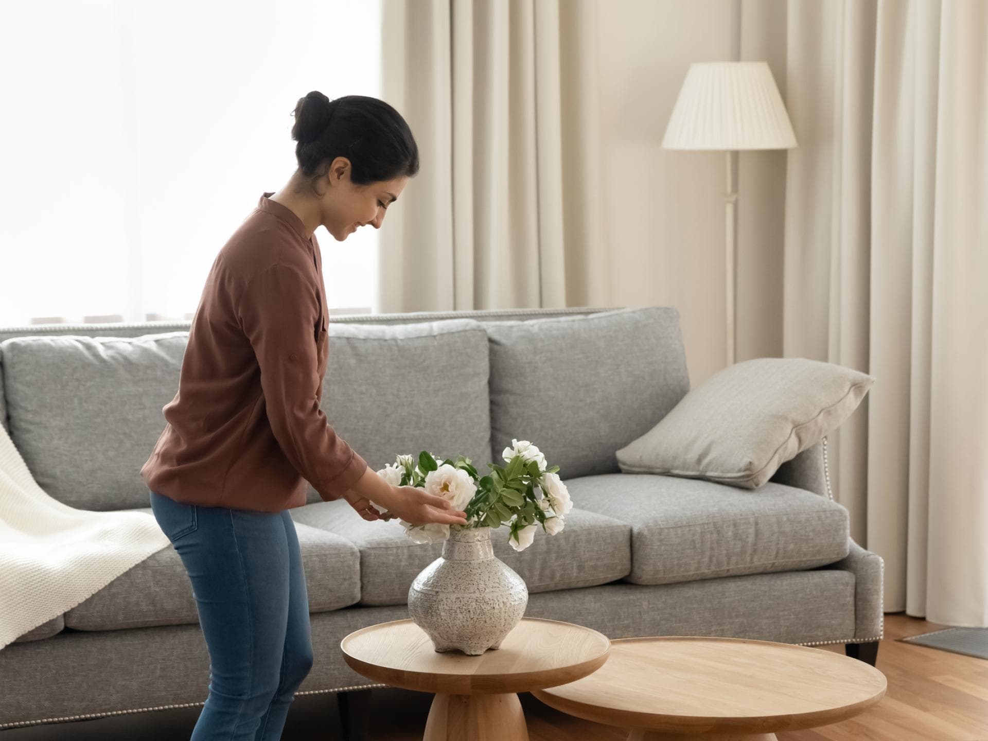 Frau dekoriert ihr Wohnzimmer mit einem Blumenstrauß auf dem Couchtisch
