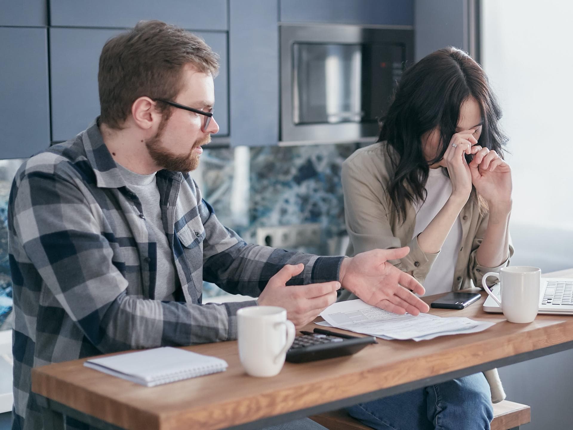 Paar sitzt am Esstisch und streitet über Finanzen