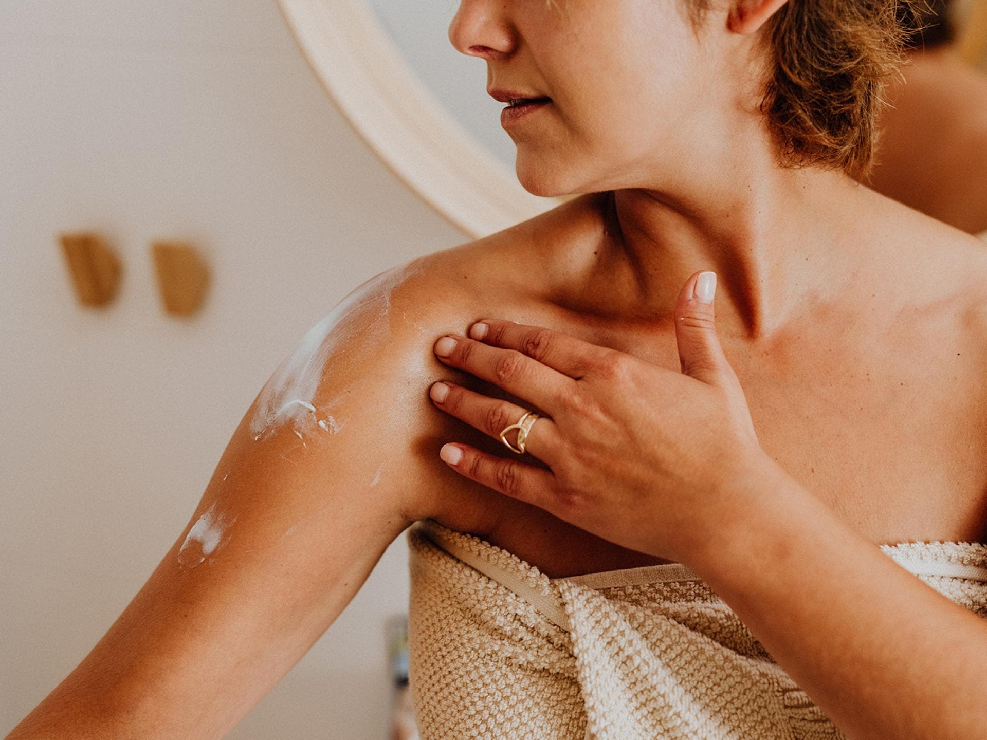 Frau cremt sich mit Bodylotion ein