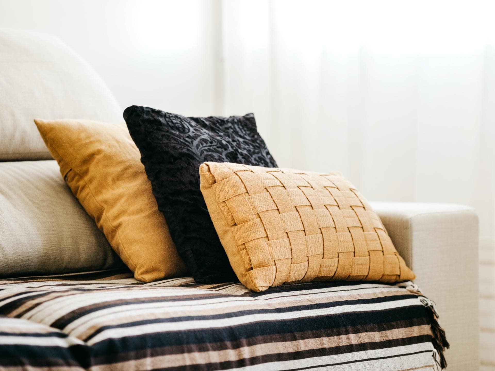 Schwarze und gelbe Kissen liegen auf einem beigefarbenen Sofa