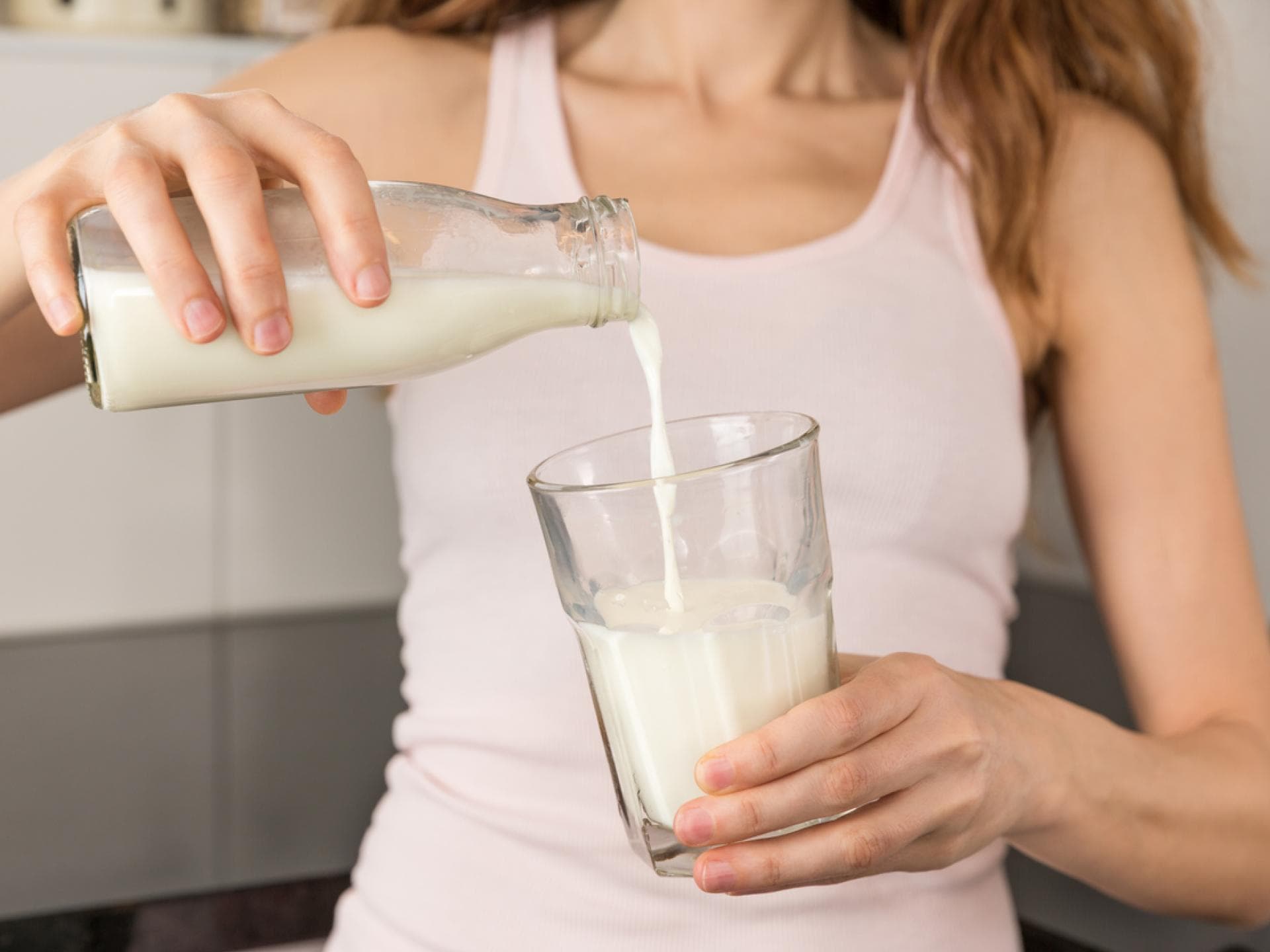 Frau gießt Milch in ein Glas