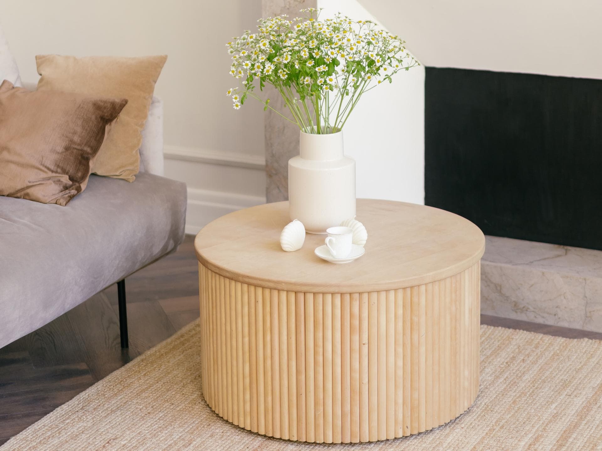 Weiße Vase steht auf einem runden Couchtisch aus Holz im Wohnzimmer