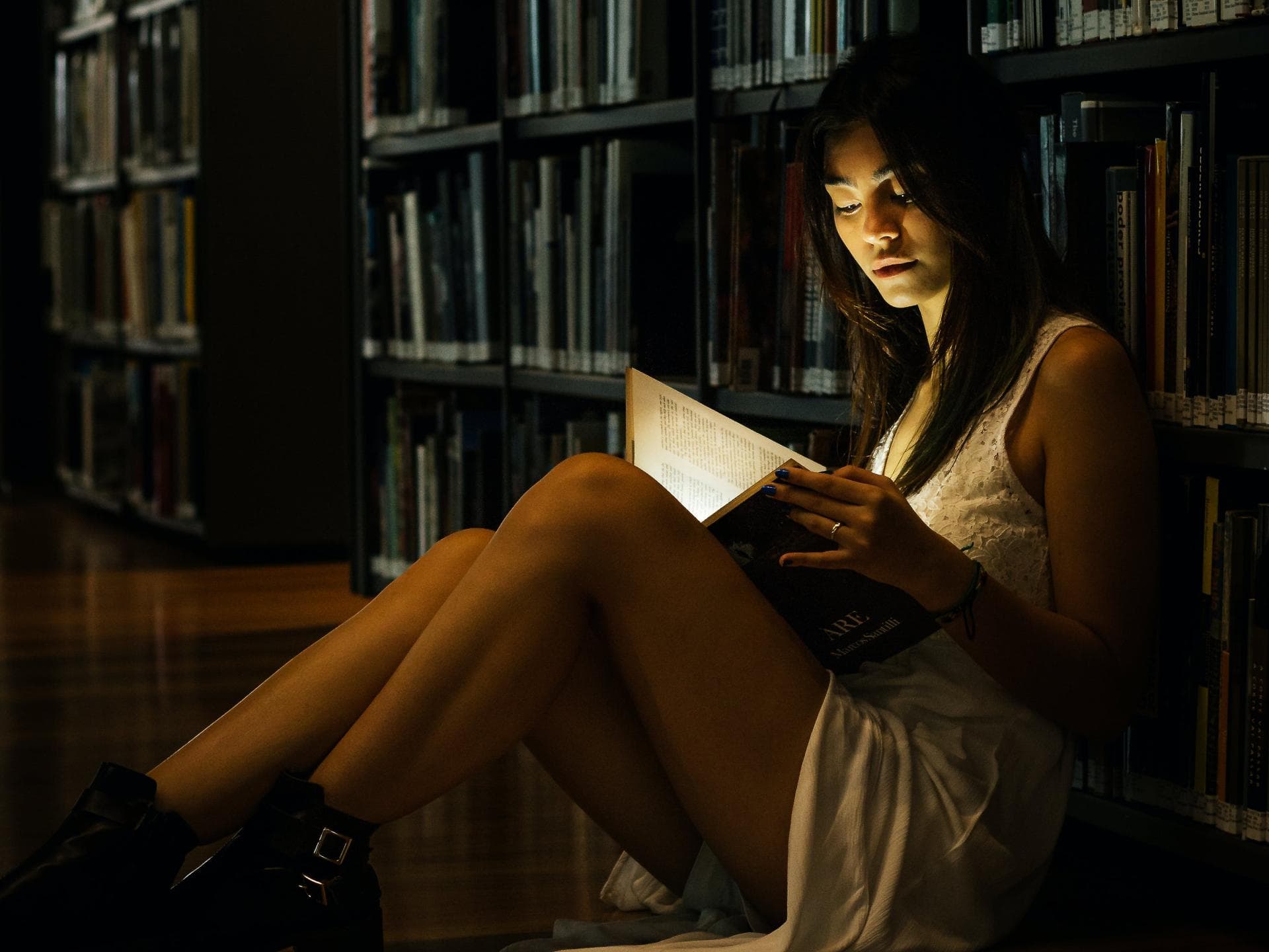 Frau im Kleid liest ein Buch in einer Bibliothek