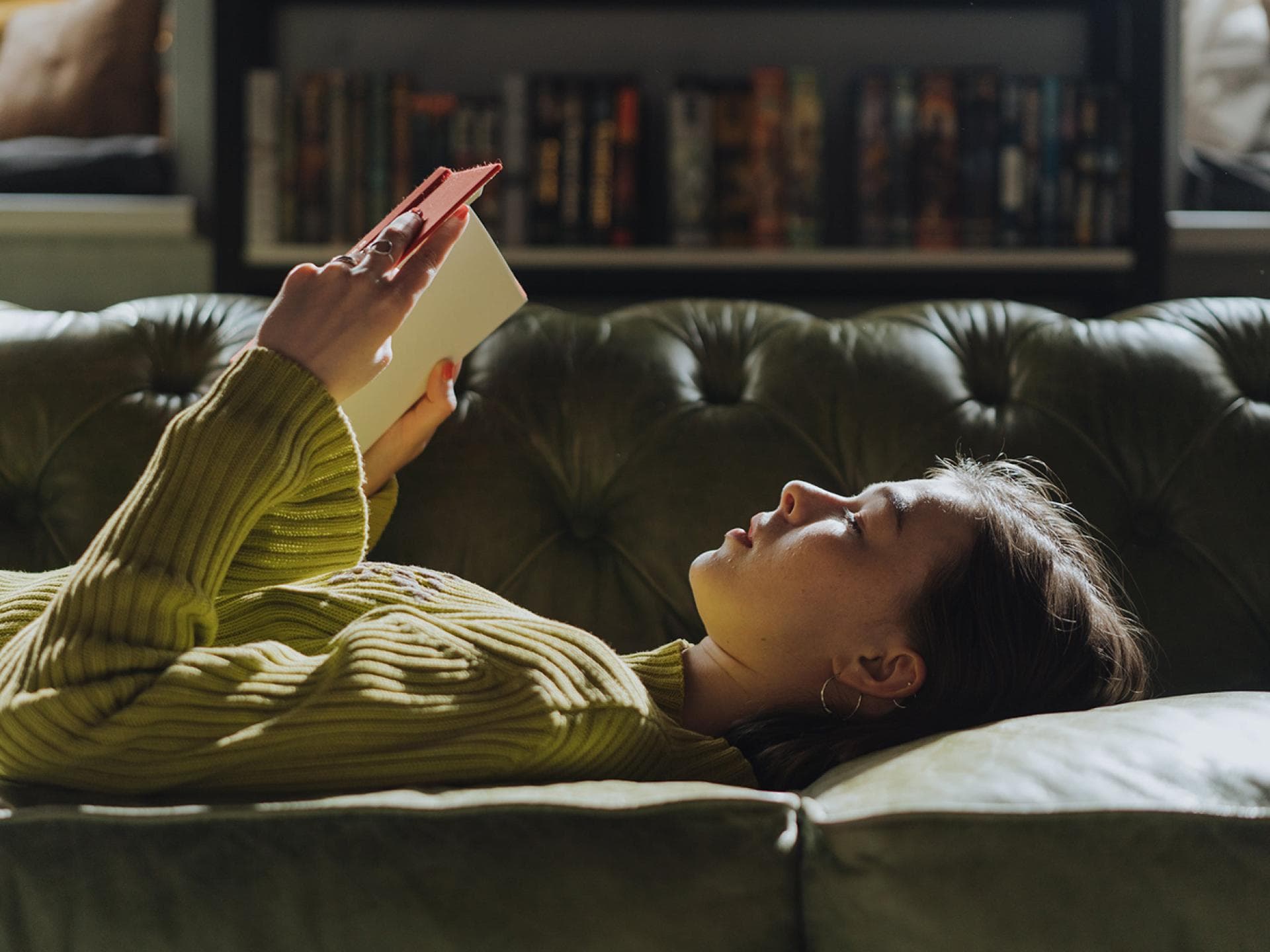 Frau liest Buch auf dem Sofa