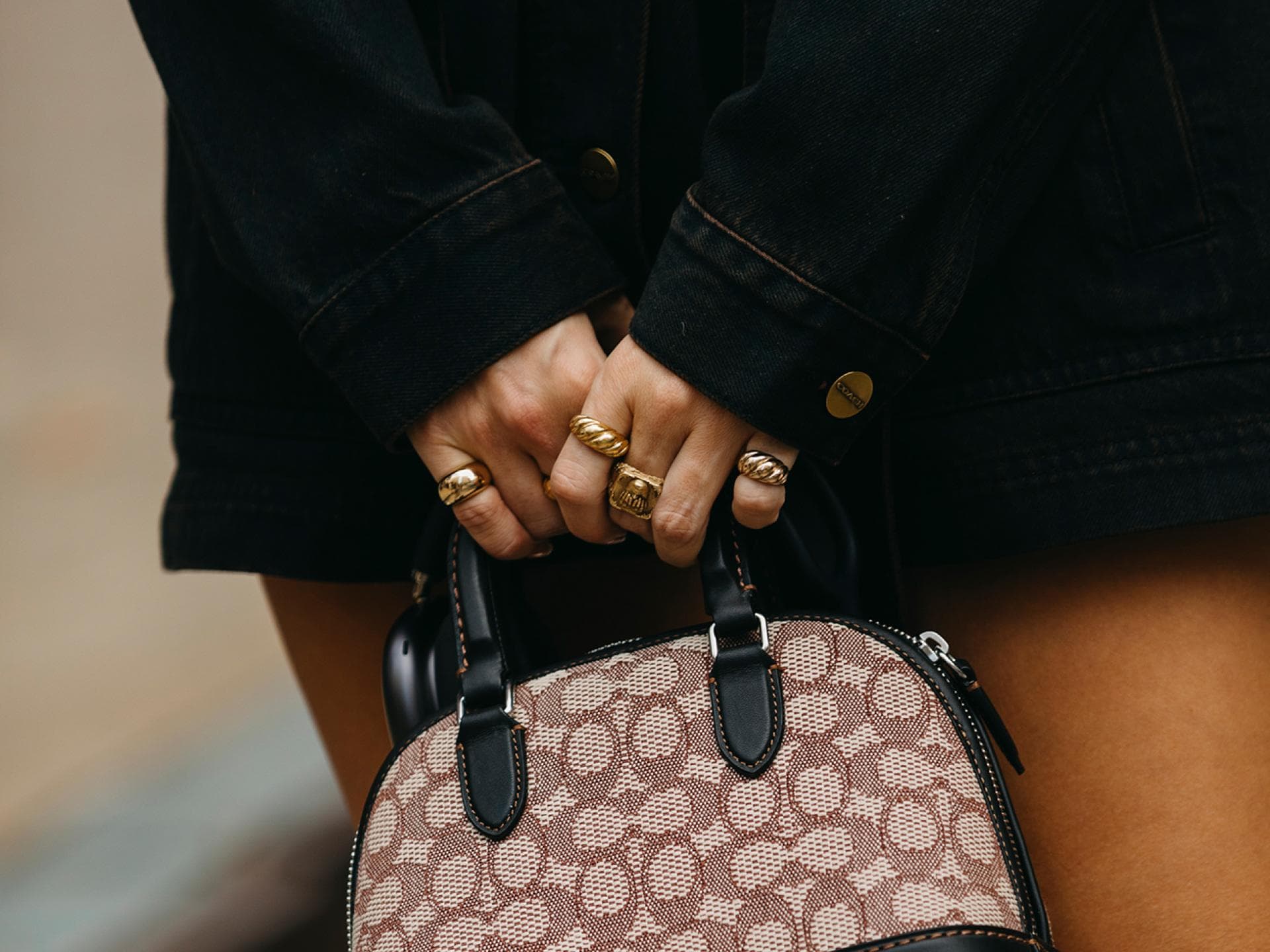 Frau mit Ringen an den Fingern hält Tasche in der Hand