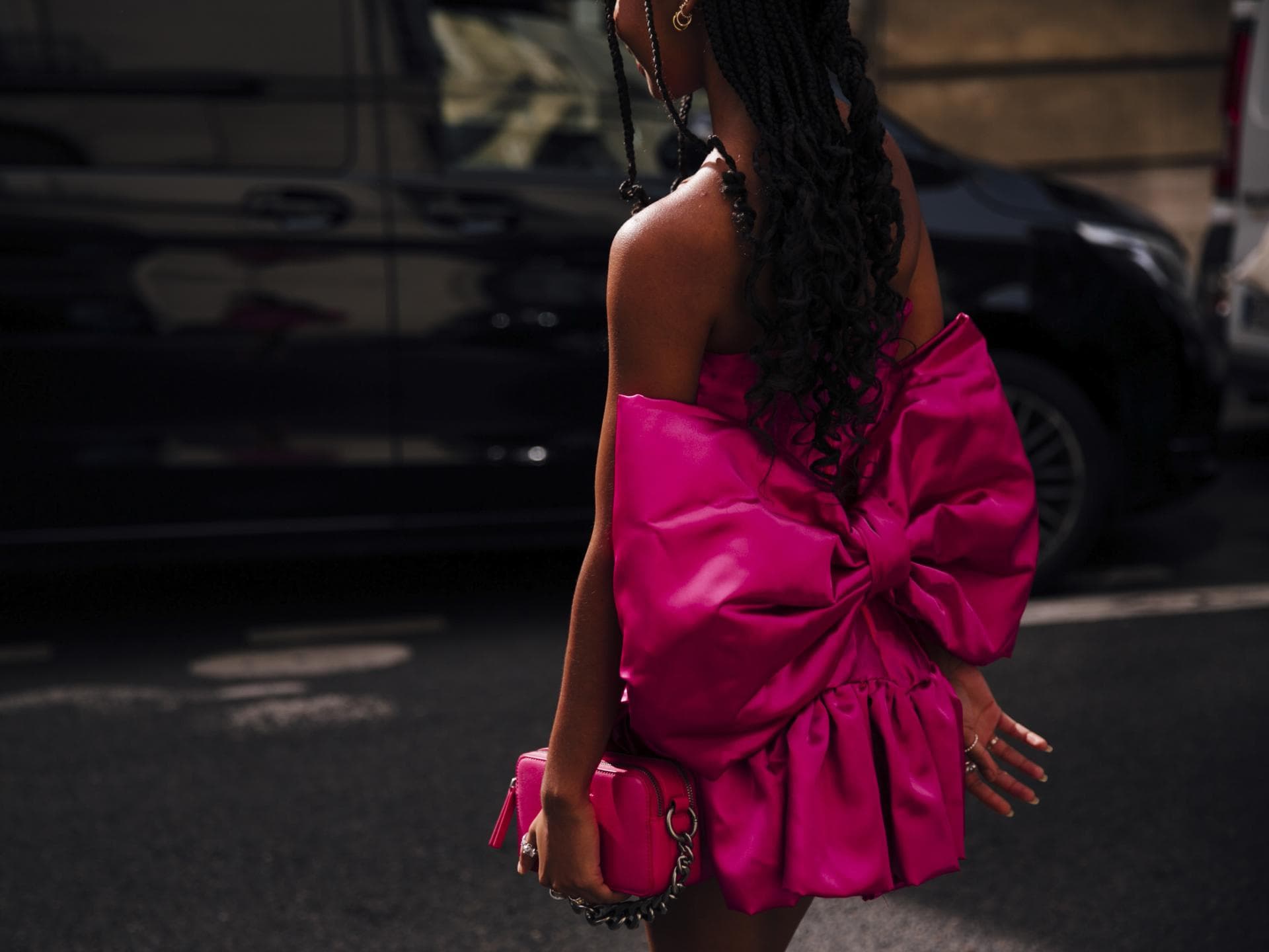 Frau trägt auf Paris Fashion Week pinkfarbenes Kleid mit Schleife und passender Tasche in der Hand