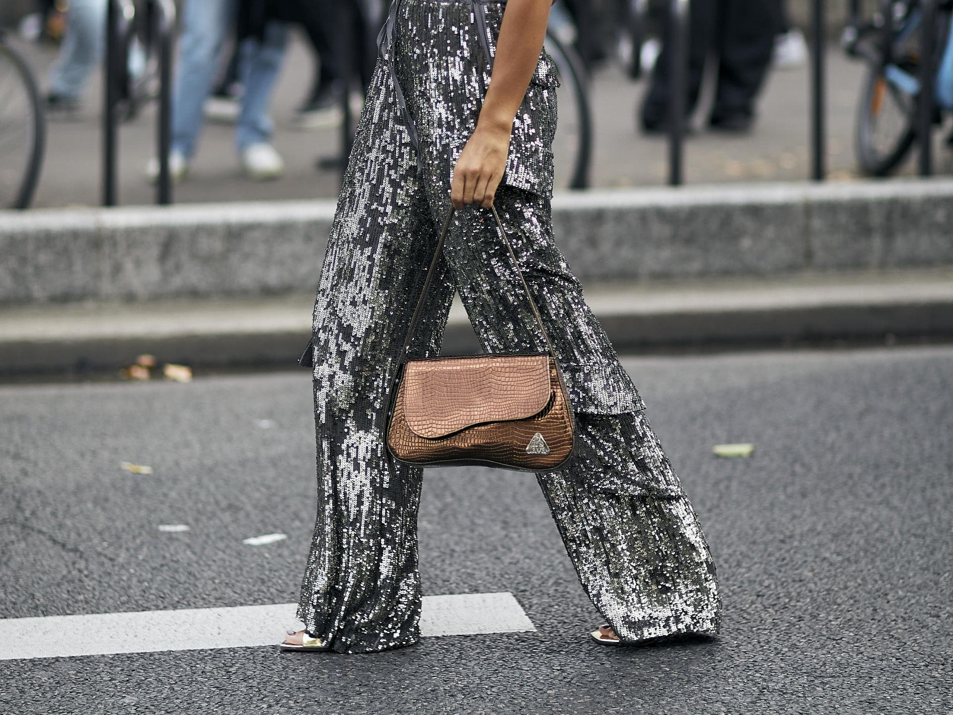Frau trägt auf Paris Fashion Week schimmernde Hose in Silber Frau trägt auf Paris Fashion Week schimmernde Hose in Silber
