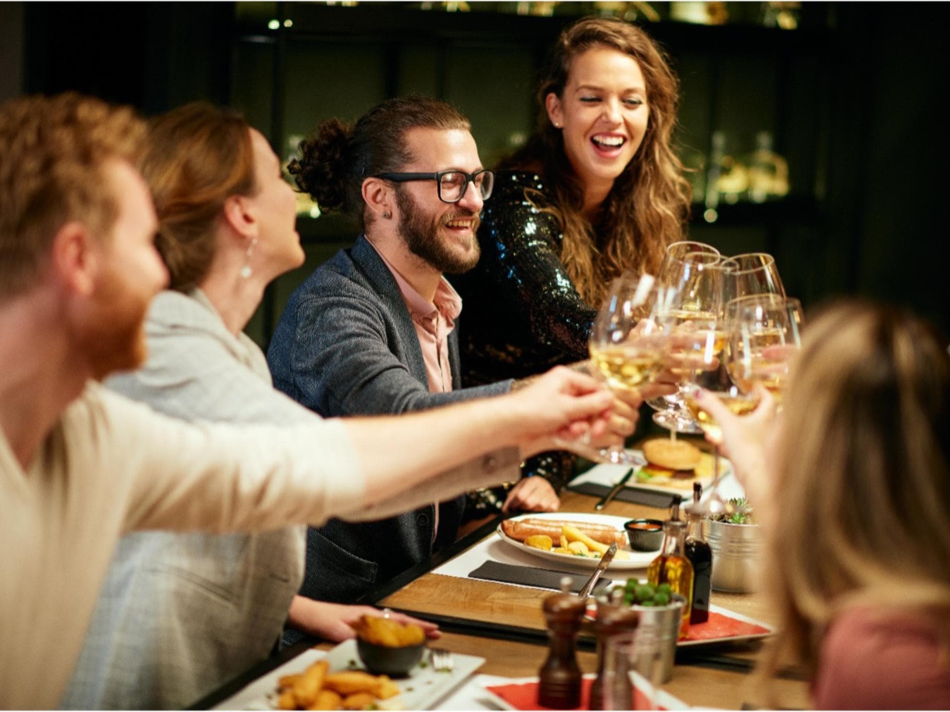 Freunde am Tisch beim Anstoßen