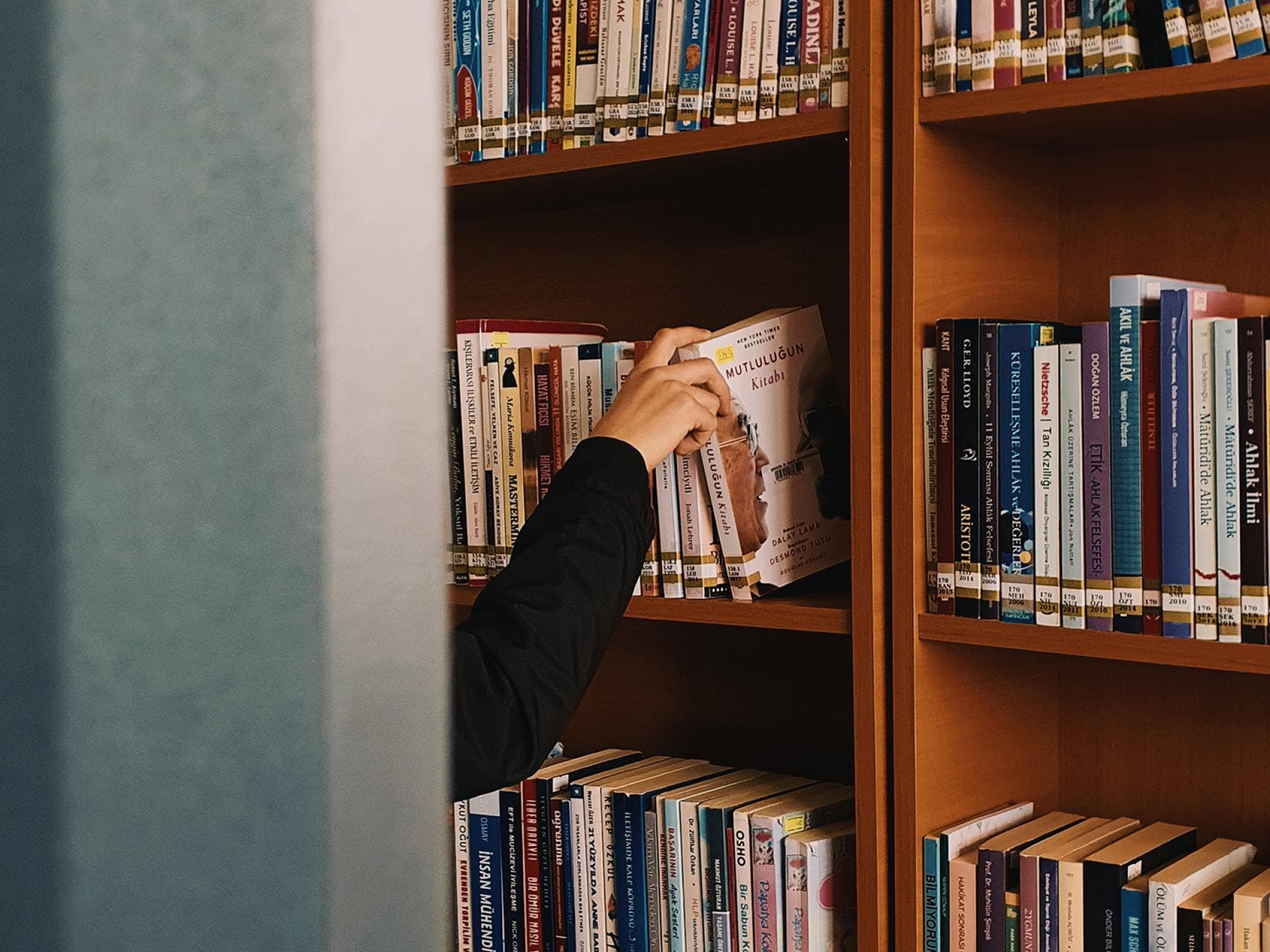 Frau greift in ein Bücherregal