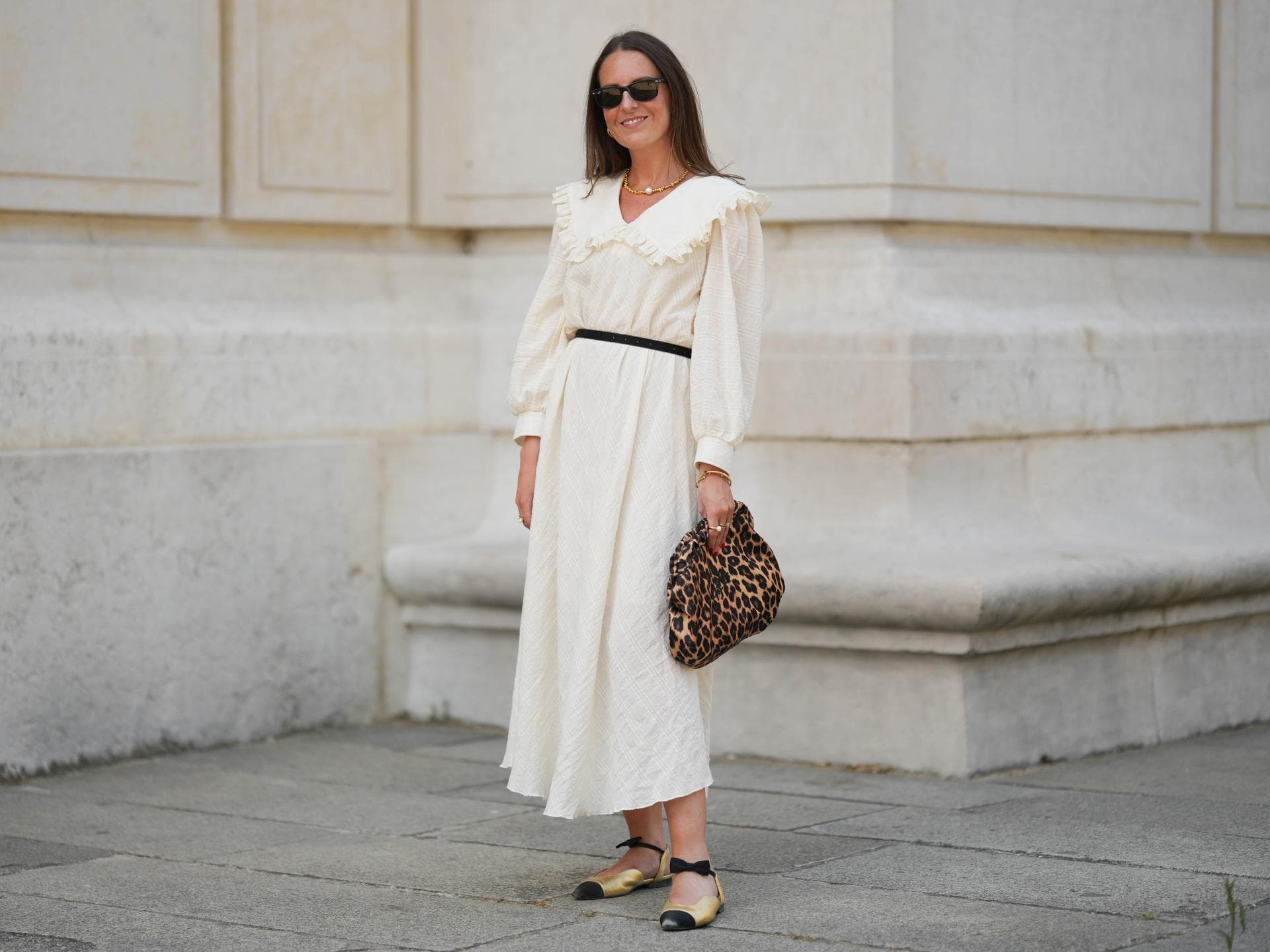 Frau in weißem Kleid und Leo-Tasche