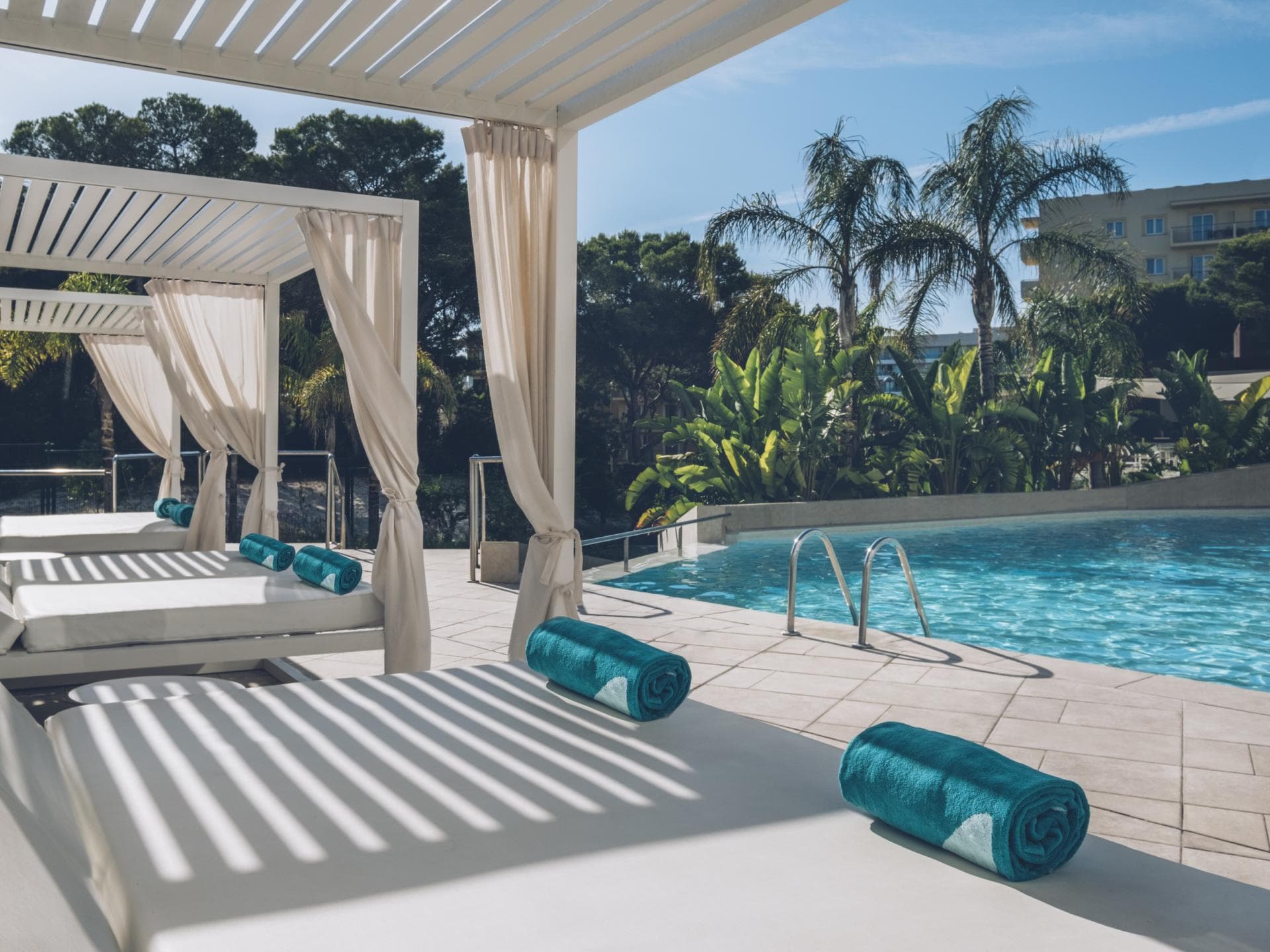 Iberostar Llaut Palma Iberostar Llaut Palma Pool mit Palmen und Liegen und türkisfarbenen Handtüchern darauf