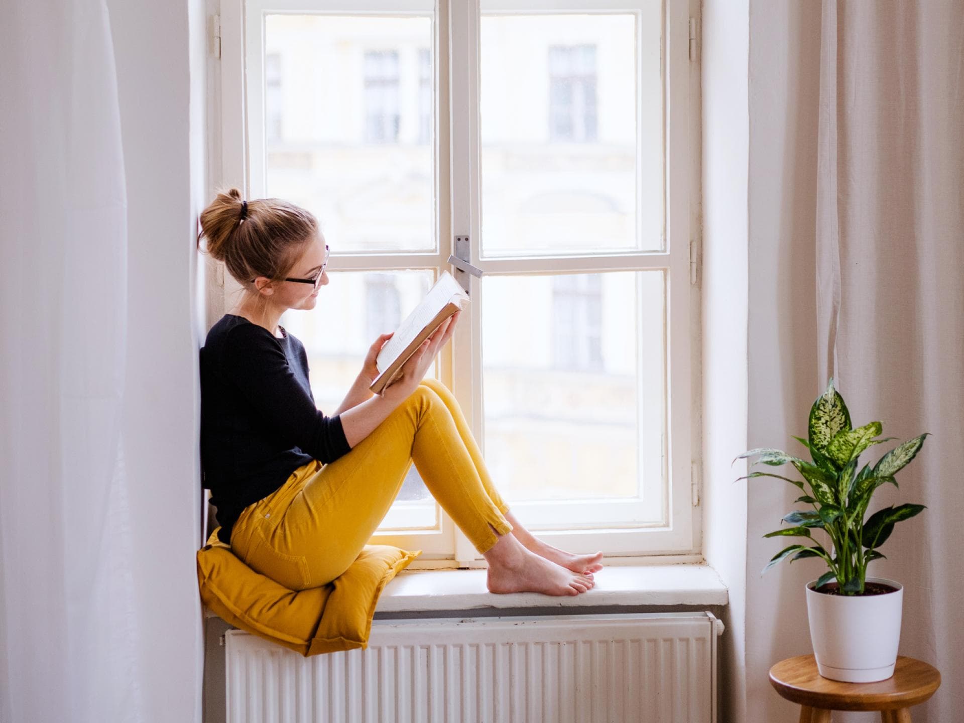 Frau liest ein Buch auf der Fensterbank
