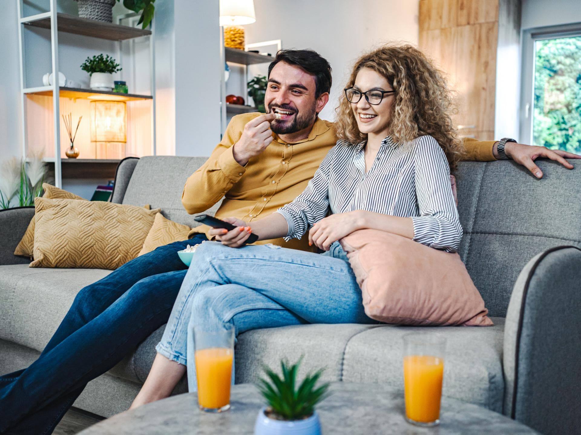 Paar sitzt auf der Couch und guckt Fernsehen