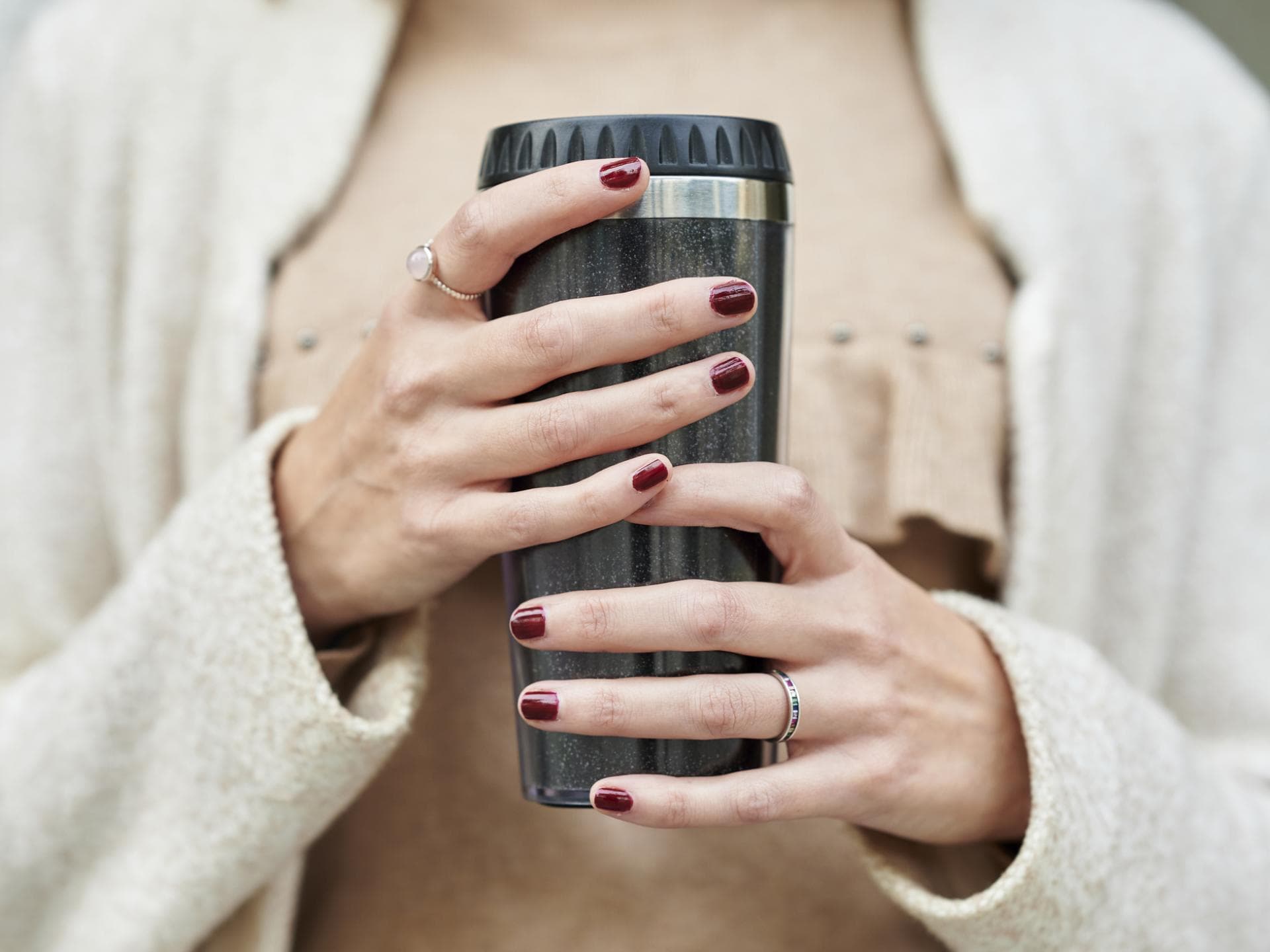 Frau hält einen Thermobecher in der Hand.