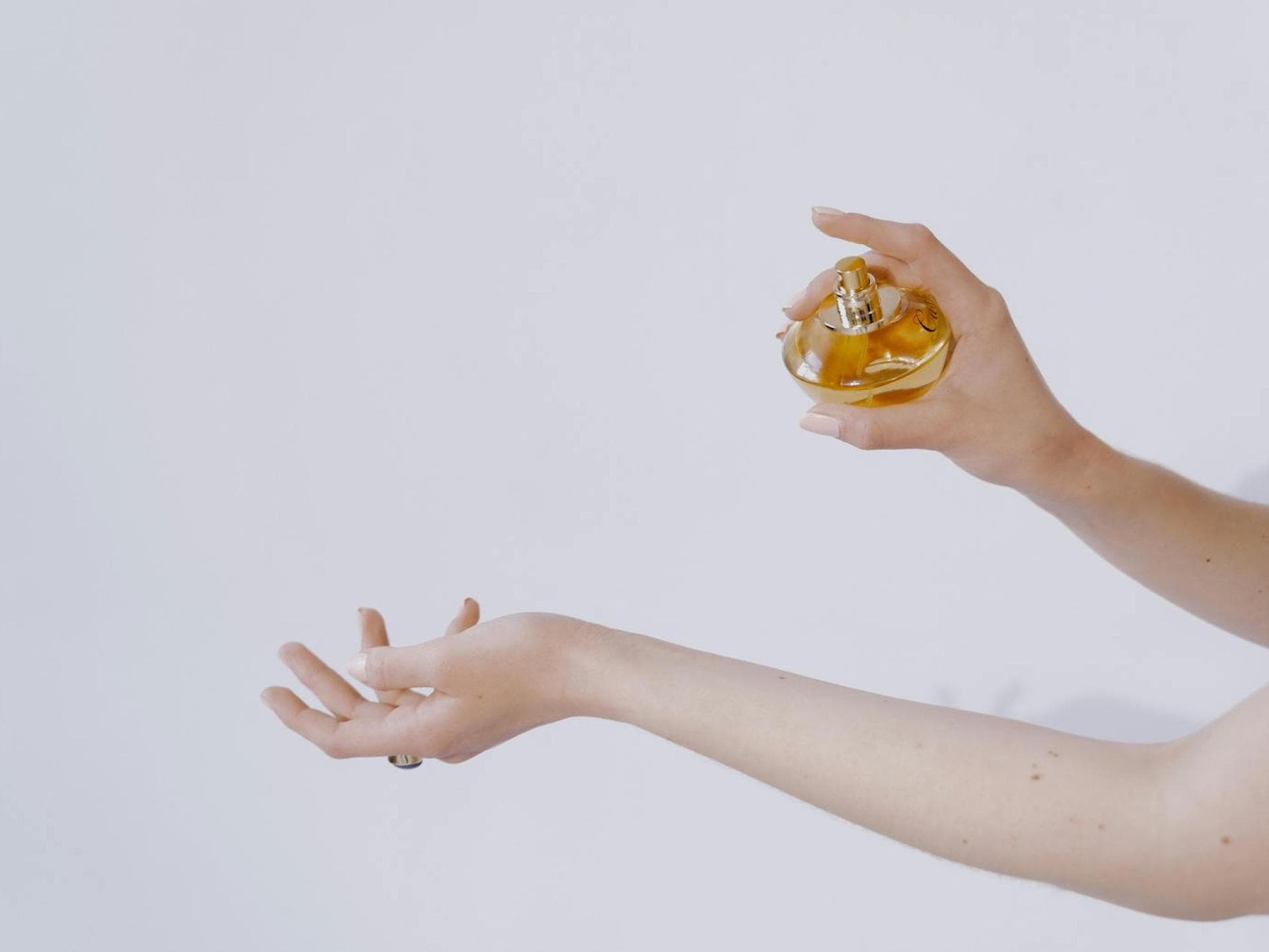 Frau sprüht Parfum auf ihren Unterarm