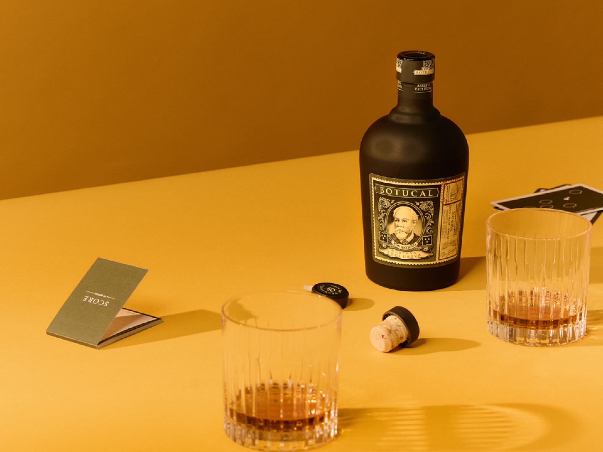 Botucal Reserva Exklusiva Rumflasche mit zwei Gläsern auf einem Tisch – ideal für elegante Drinks wie den Old Fashioned. Botucal Reserva Exklusiva Rumflasche mit zwei Gläsern auf einem Tisch – ideal für elegante Drinks wie den Old Fashioned.
