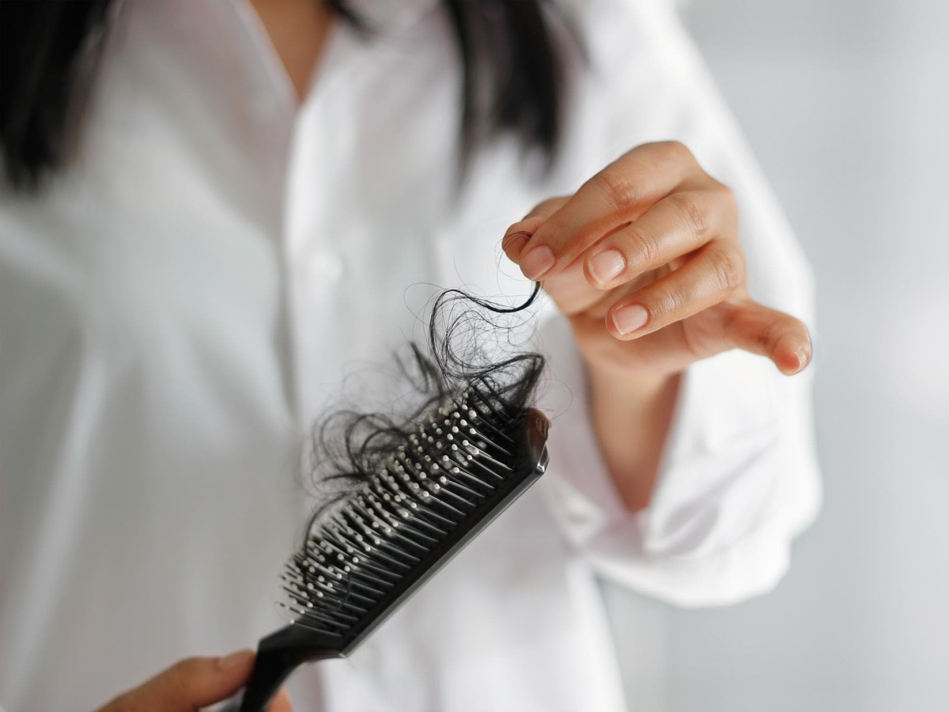 Eine Frau hält eine Bürste mit Haaren in der Hand