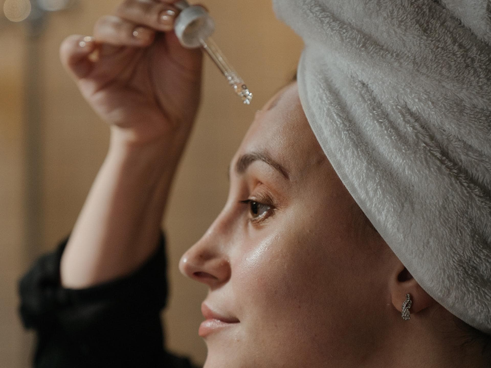 Eine Frau trägt ein Serum auf ihr Gesicht auf