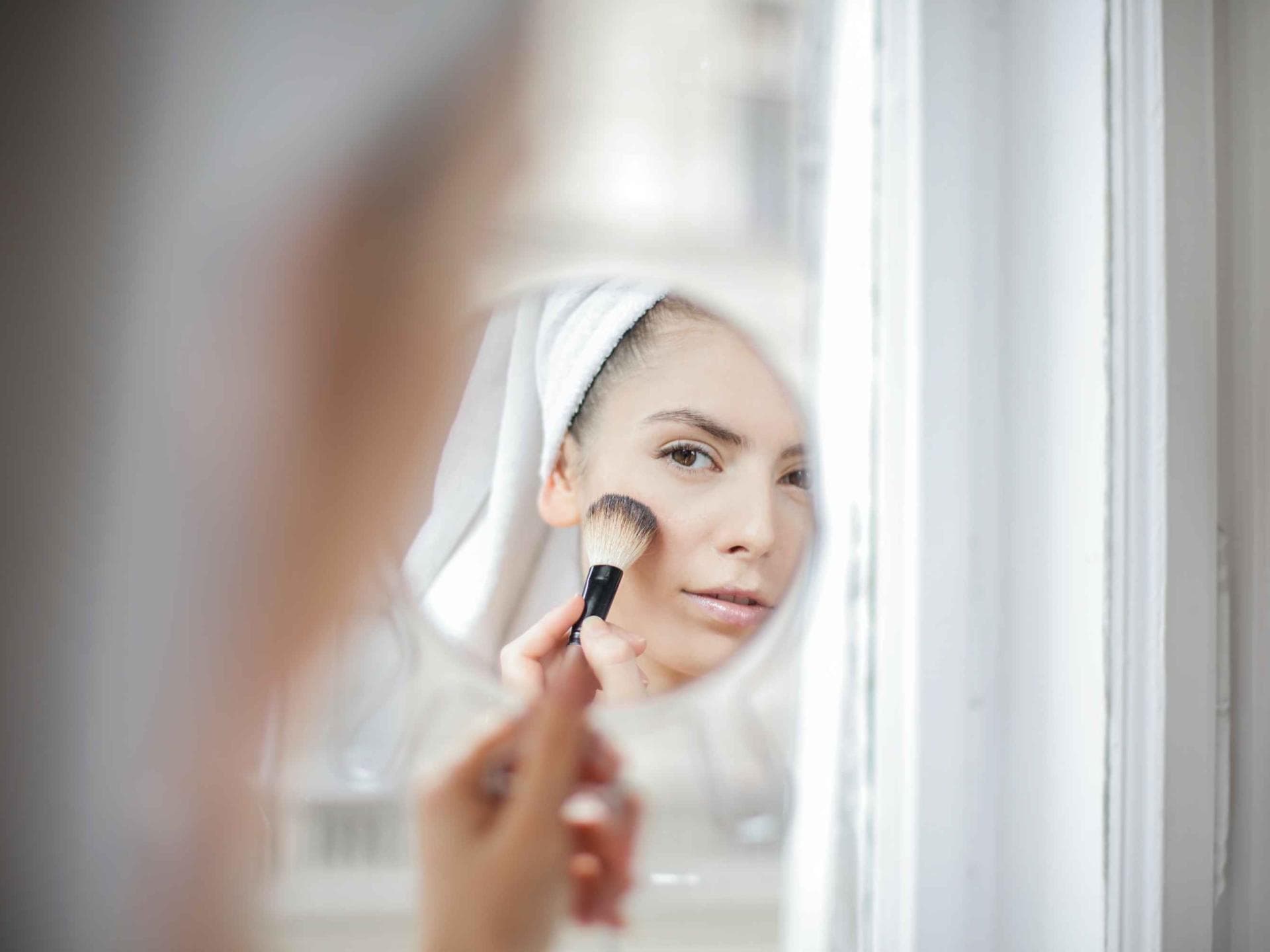 Frau mit Make-up Pinsel schaut in den Spiegel