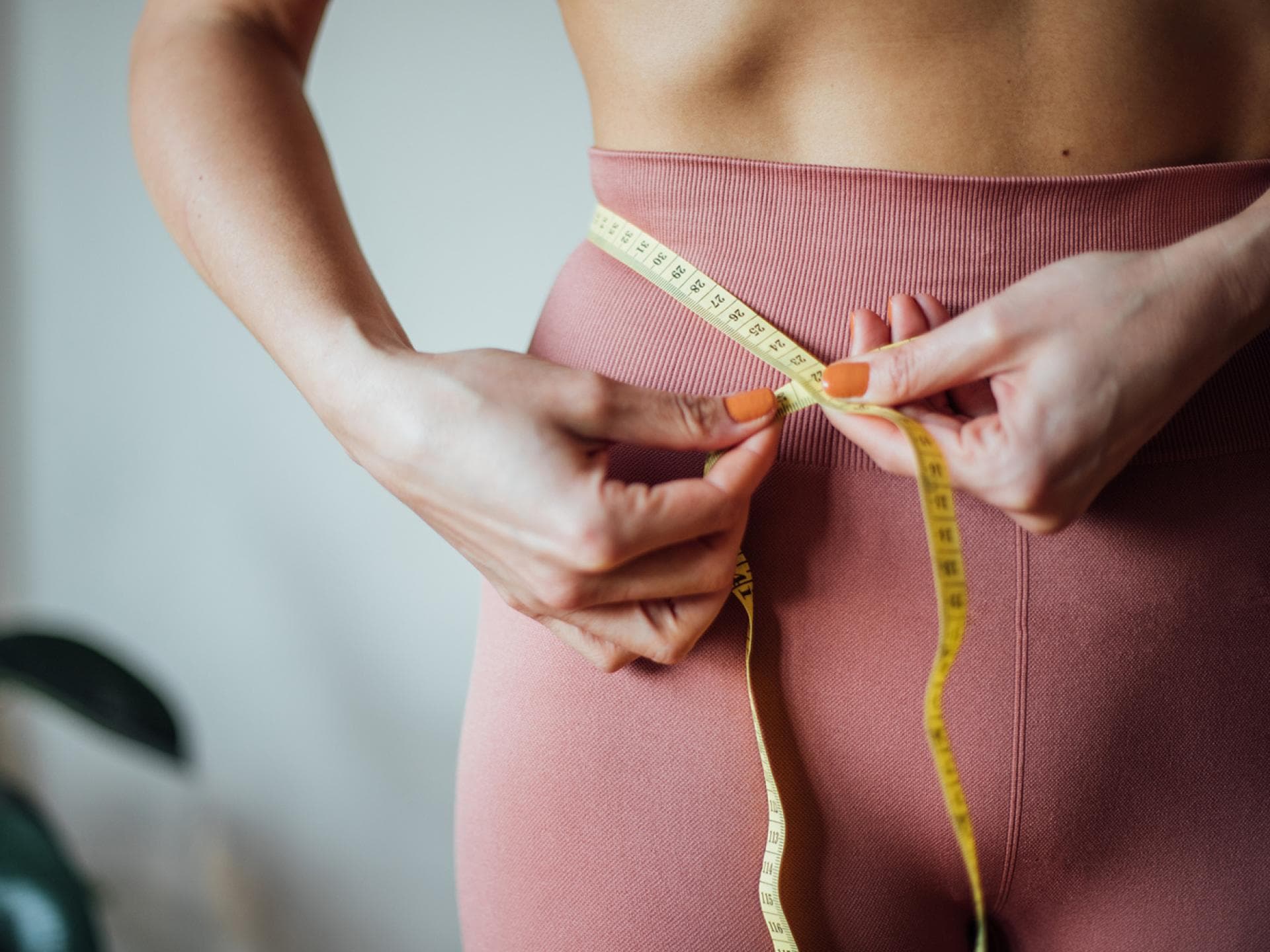 Frau misst ihre Taille mit einem Maßband
