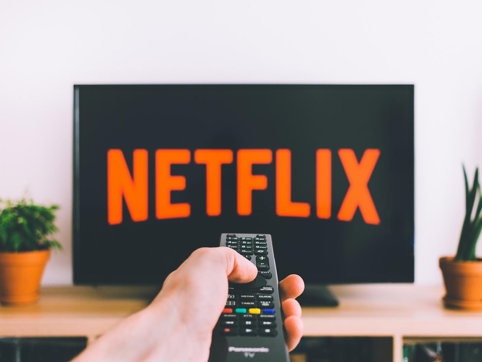 Person schaut Netflix und bedient die Fernbedienung
