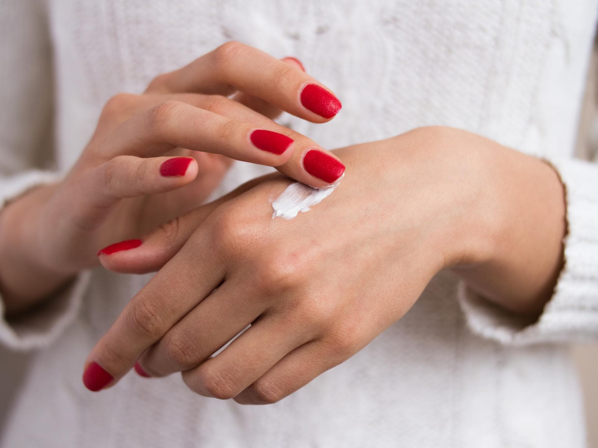 Frau trägt sich eine pflegende Handcreme auf