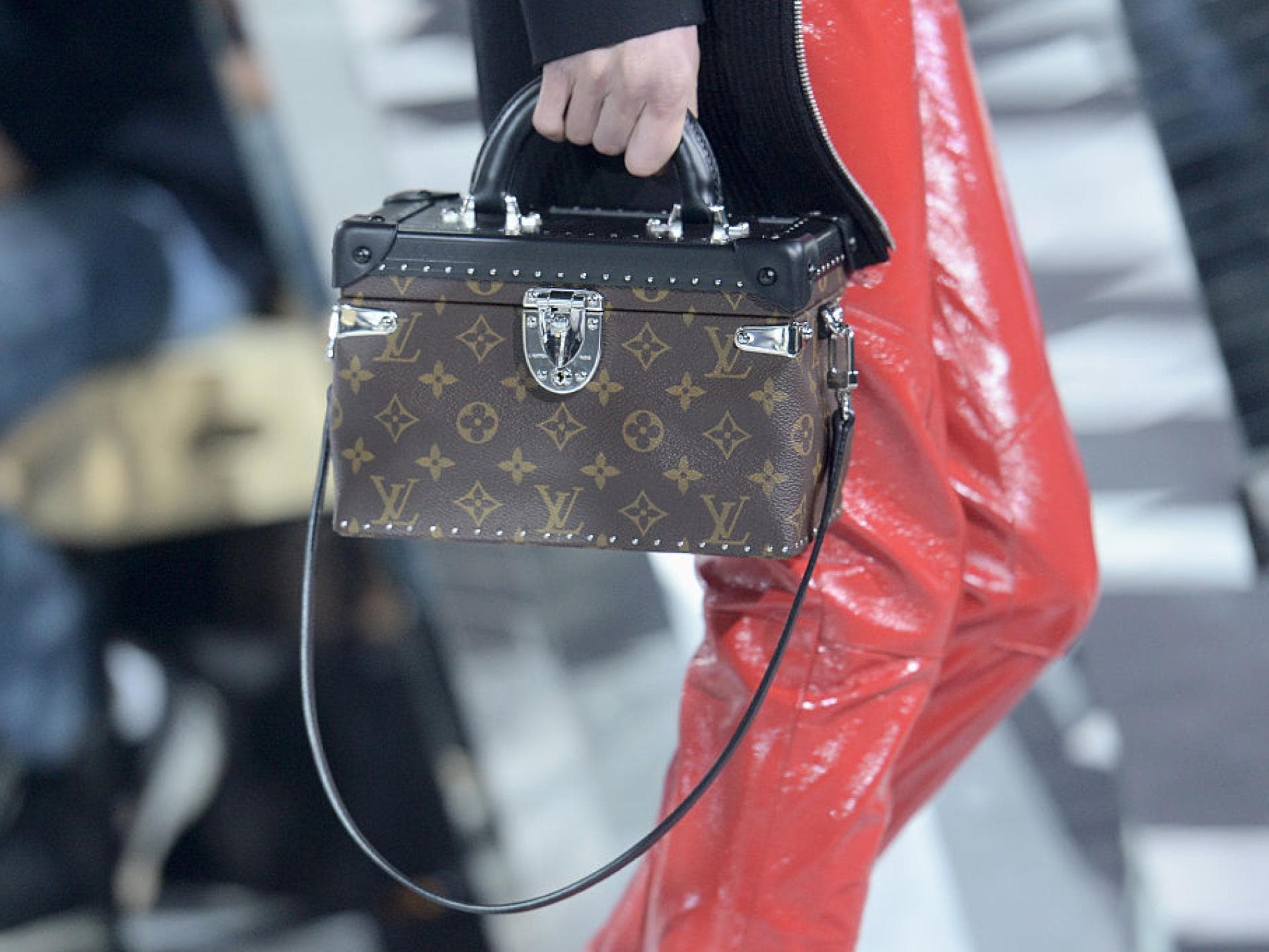 Eine Frau trägt eine Tasche im Koffer-Stil mit dem Louis Vuitton Monogram-Muster
