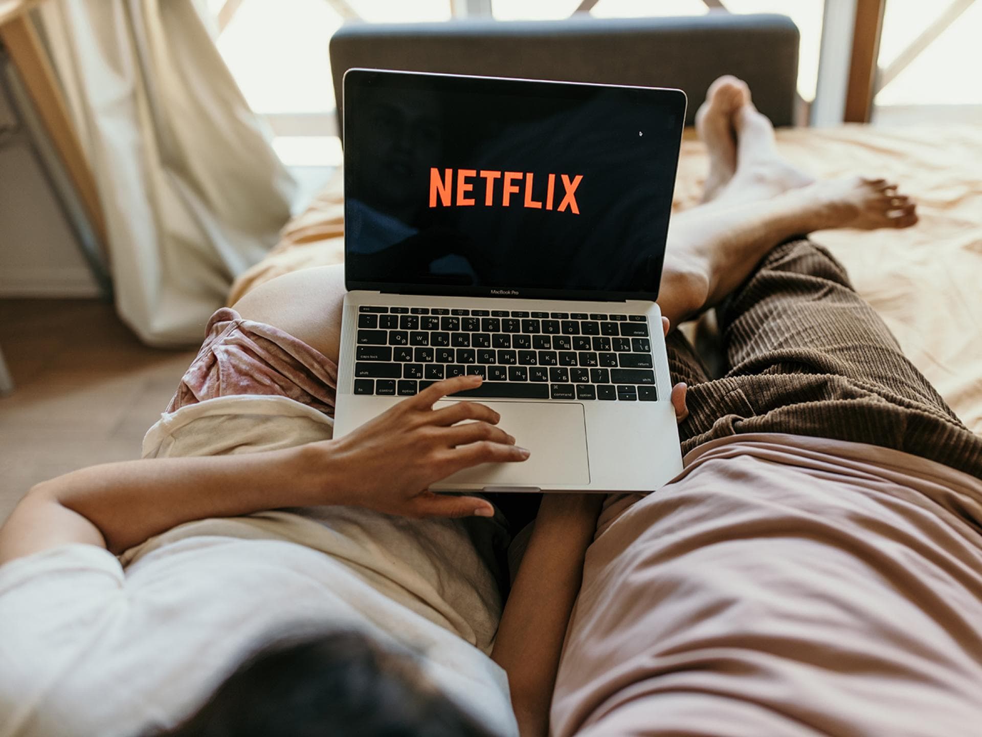 Paar liegt im Bett mit einem Laptop