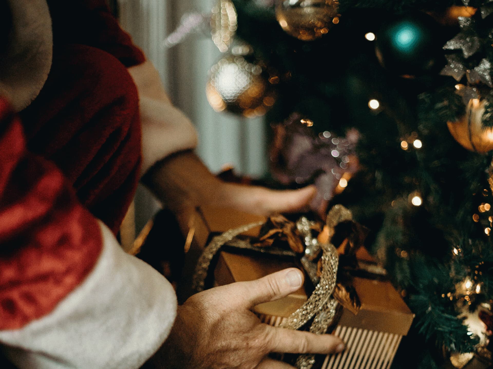 Weihnachtsmann legt Geschenke unter den Christbaum