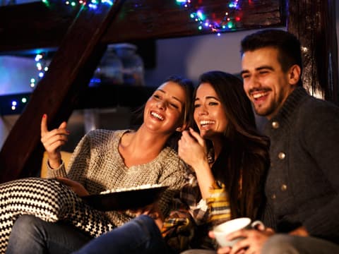 Gruppe sitzt vor Fernseher Lichterkette Freunde