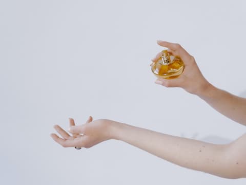 Frau sprüht sich mit Parfum ein 