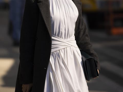 Frau trägt weißes Kleid und schwarzen Mantel New York Fashion Week 