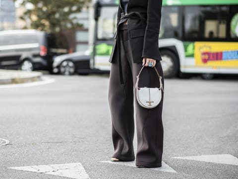 Frau mit Hosenanzug und weißer Tasche