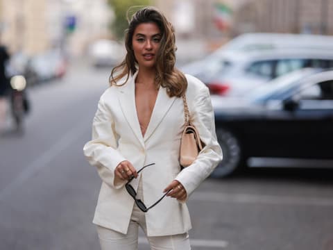 Frau trägt einen hellen Leinen-Blazer mit beiger Chanel-Tasche